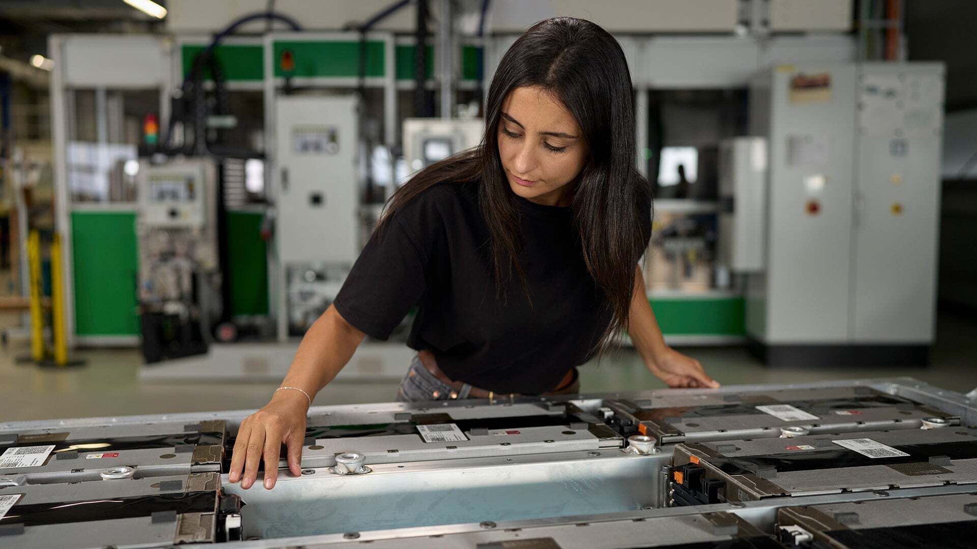 Aylin Reyhan ist mit einer Hochvolt-Batterie von Audi beschäftigt, die vor ihr steht