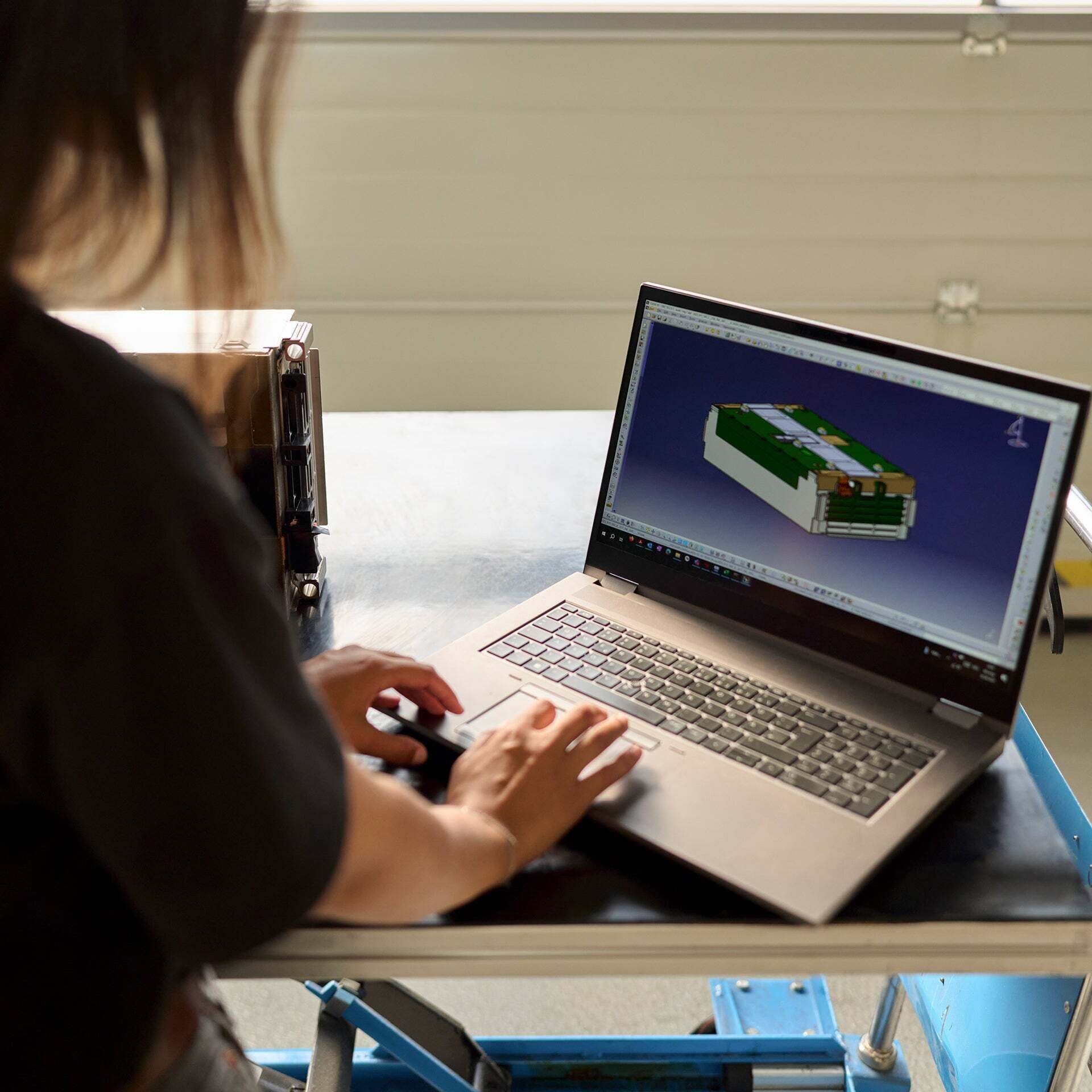 Aylin Reyhan schaut auf den Bildschirm ihres Desktops, worauf sie eine 3D-Ansicht einer Autobatterie hat