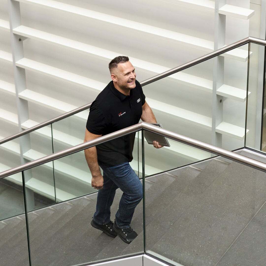 Andreas Walter hält einen Laptop in der Hand und geht eine Treppe hoch.