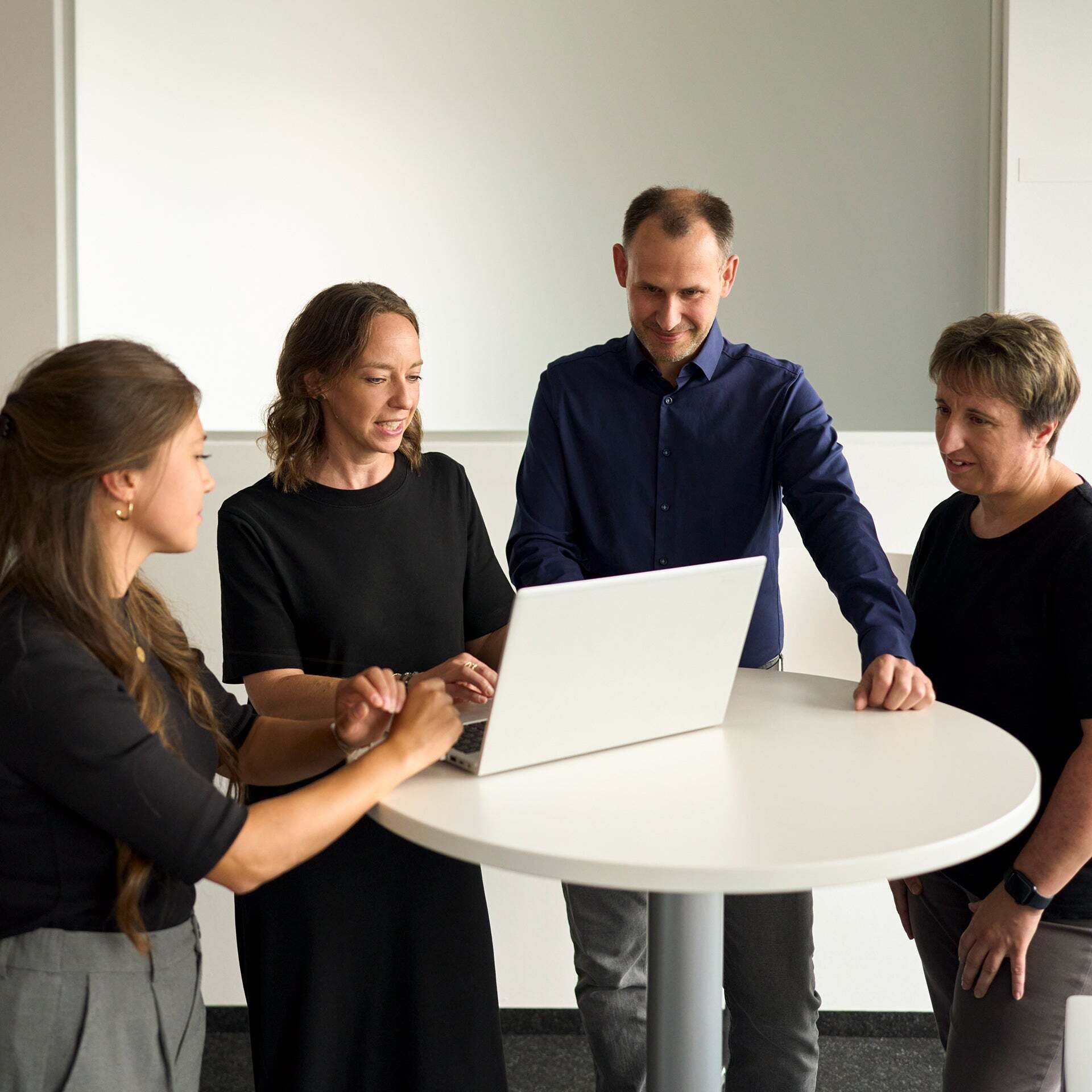Melanie Limmer talks to colleagues and shows them something on a laptop