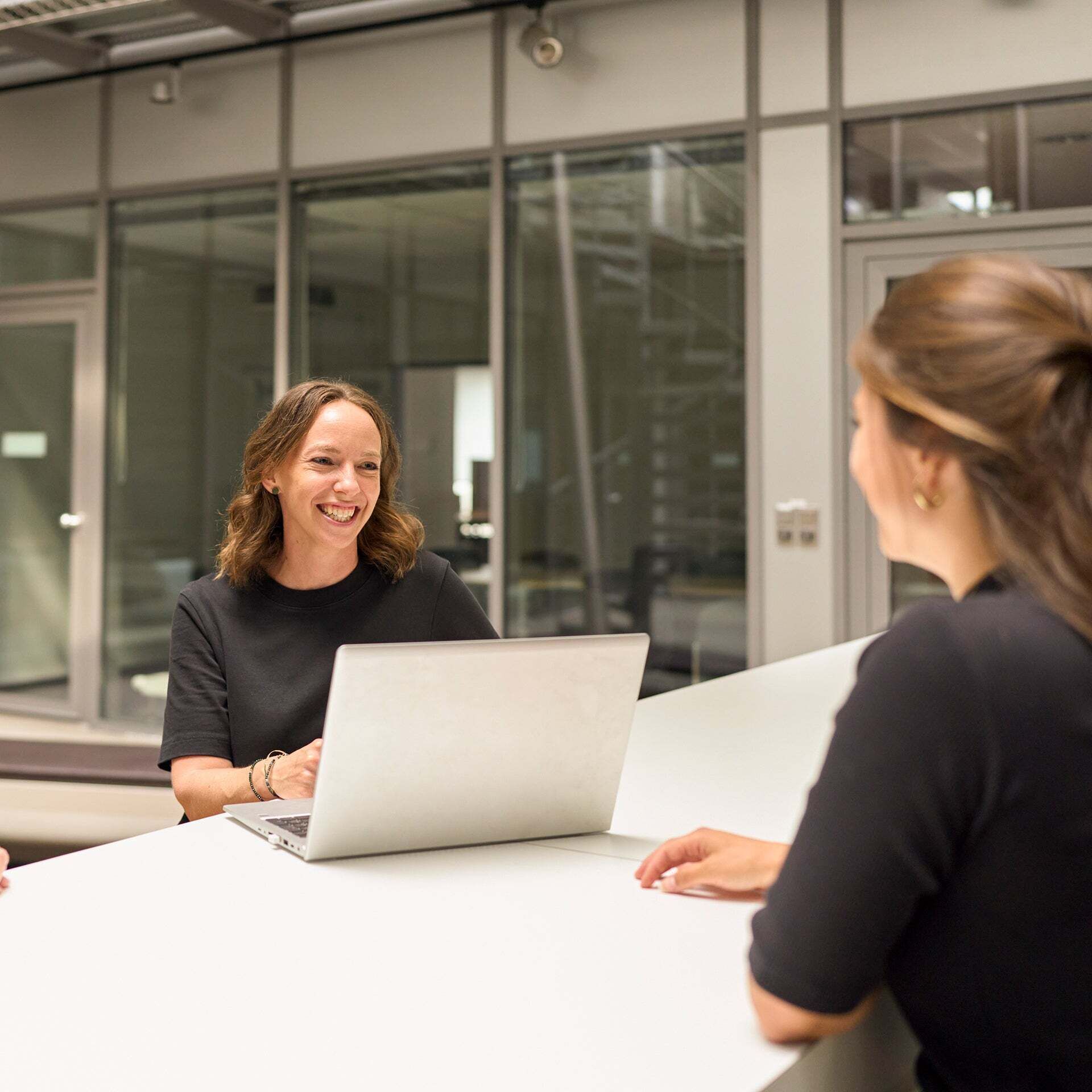 Melanie Limmer smiles at a colleague and has a laptop in front of her