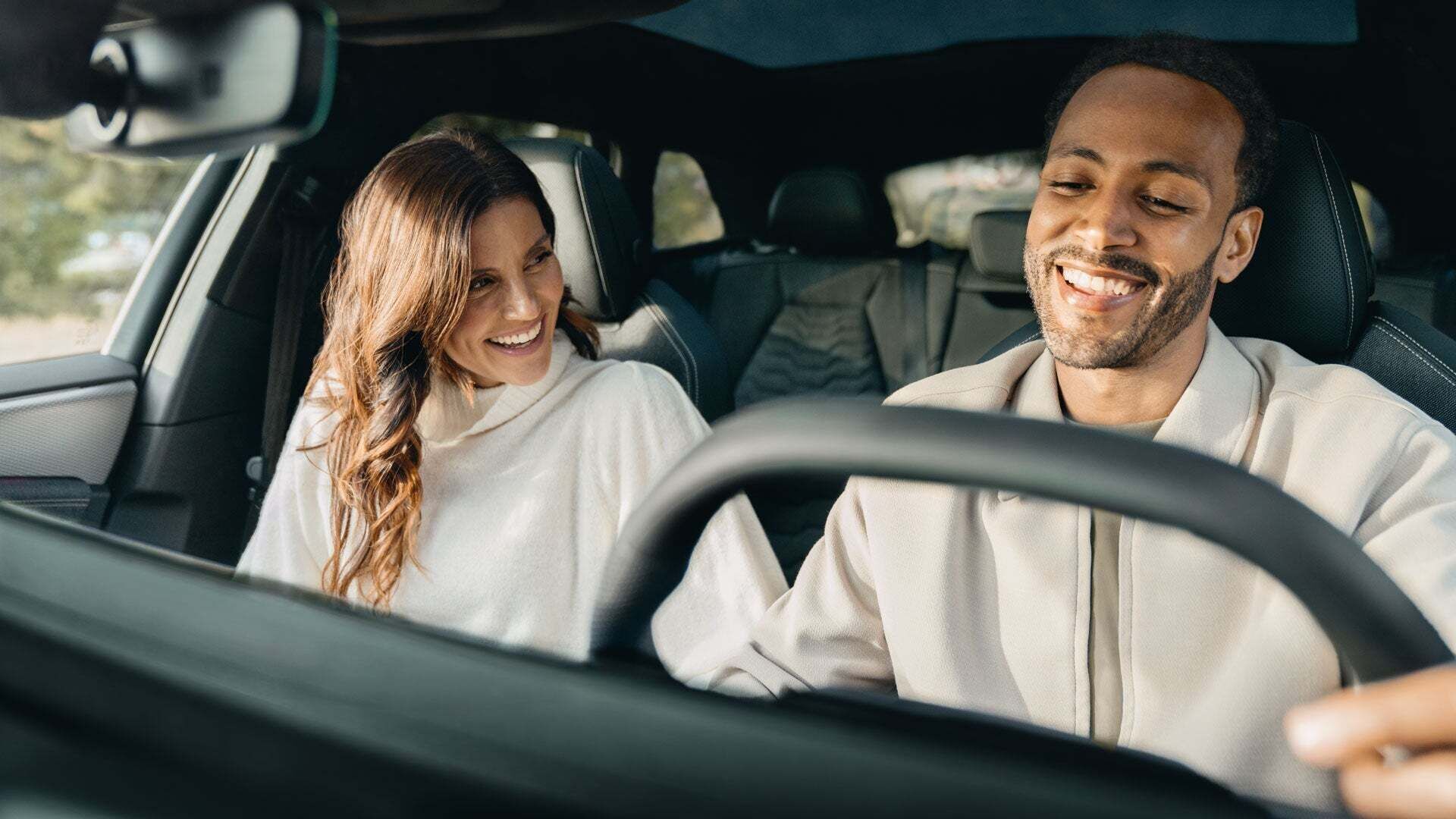 Paar sitzt freudig lachend auf den Vordersitzen ihres Audi