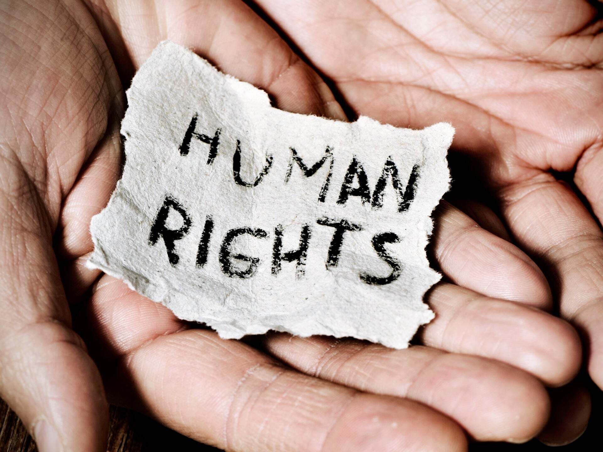 Hands holding a piece of paper that reads Human Rights