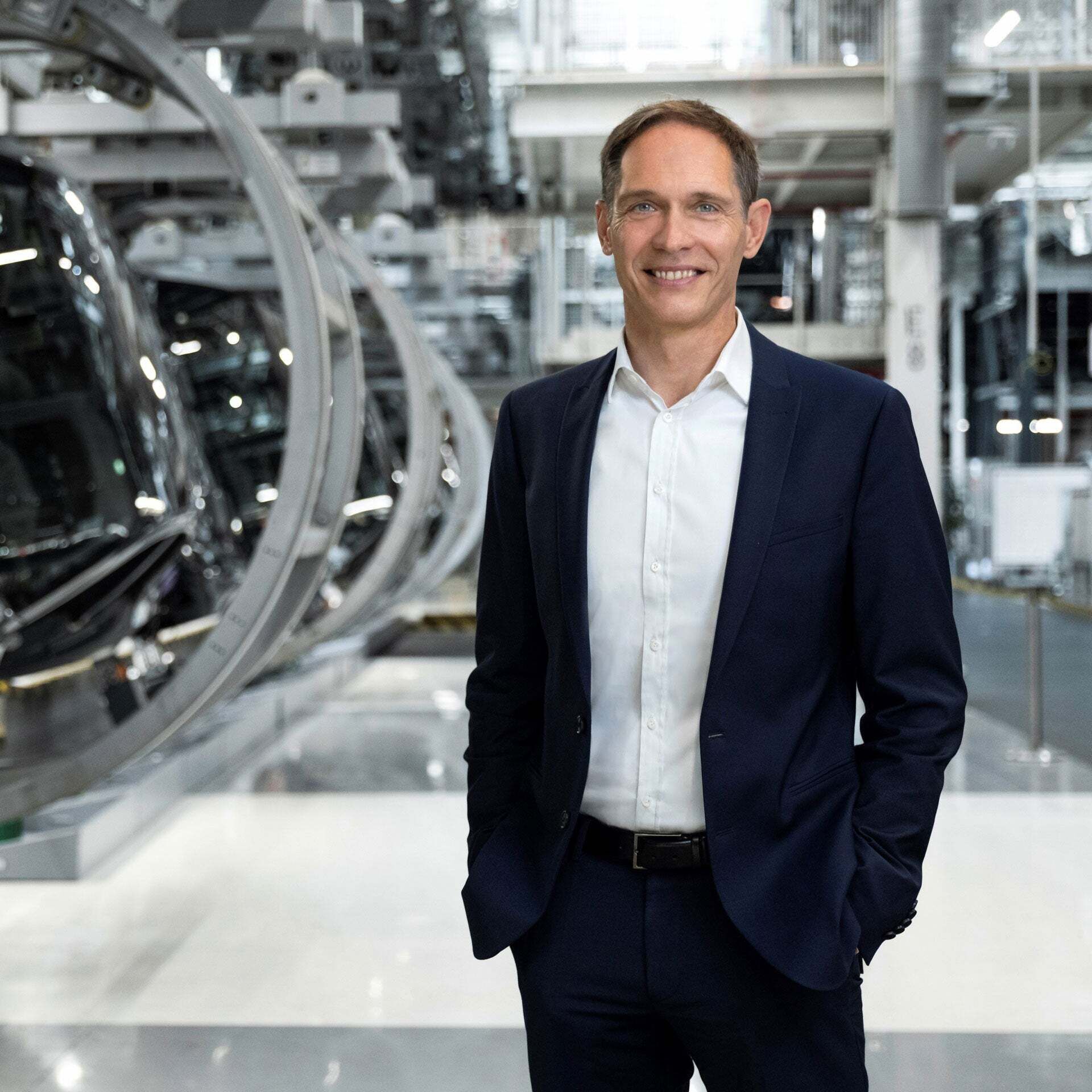 Gerd Walker; Member of the Board of Management of AUDI AG Production and Logistics; stands smiling cheerfully in a production hall.