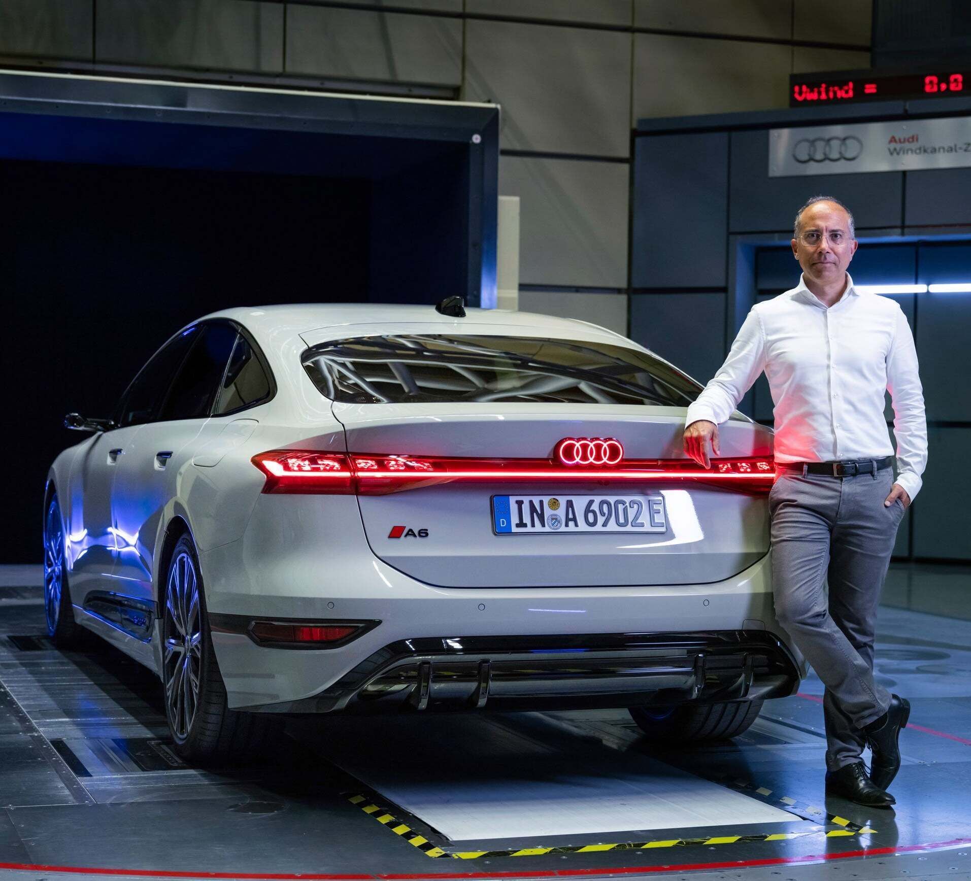 Moni Islam leans against the rear of the Audi A6 e-tron