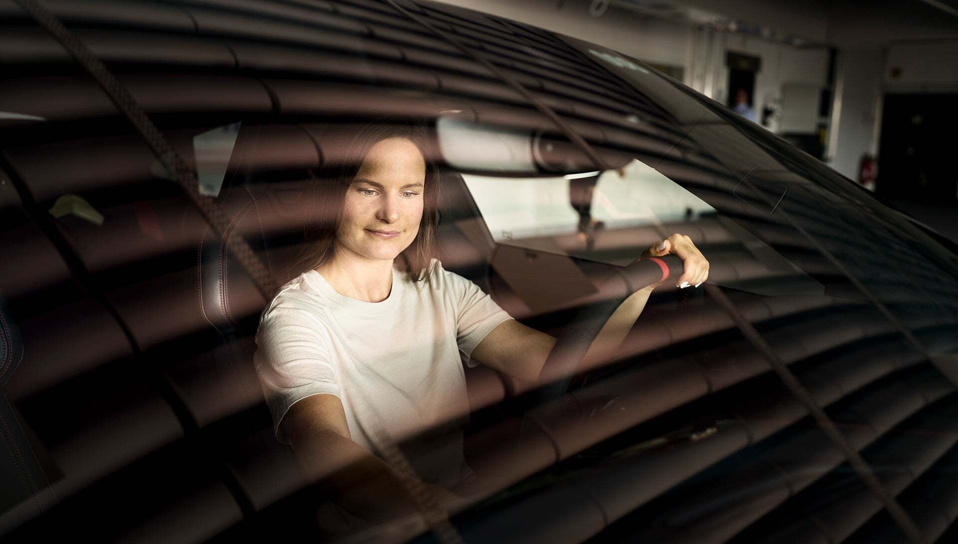 Melanie Schillinger sitzt in einem Audi und schaut nach unten mit einer Hand am Lenkrad