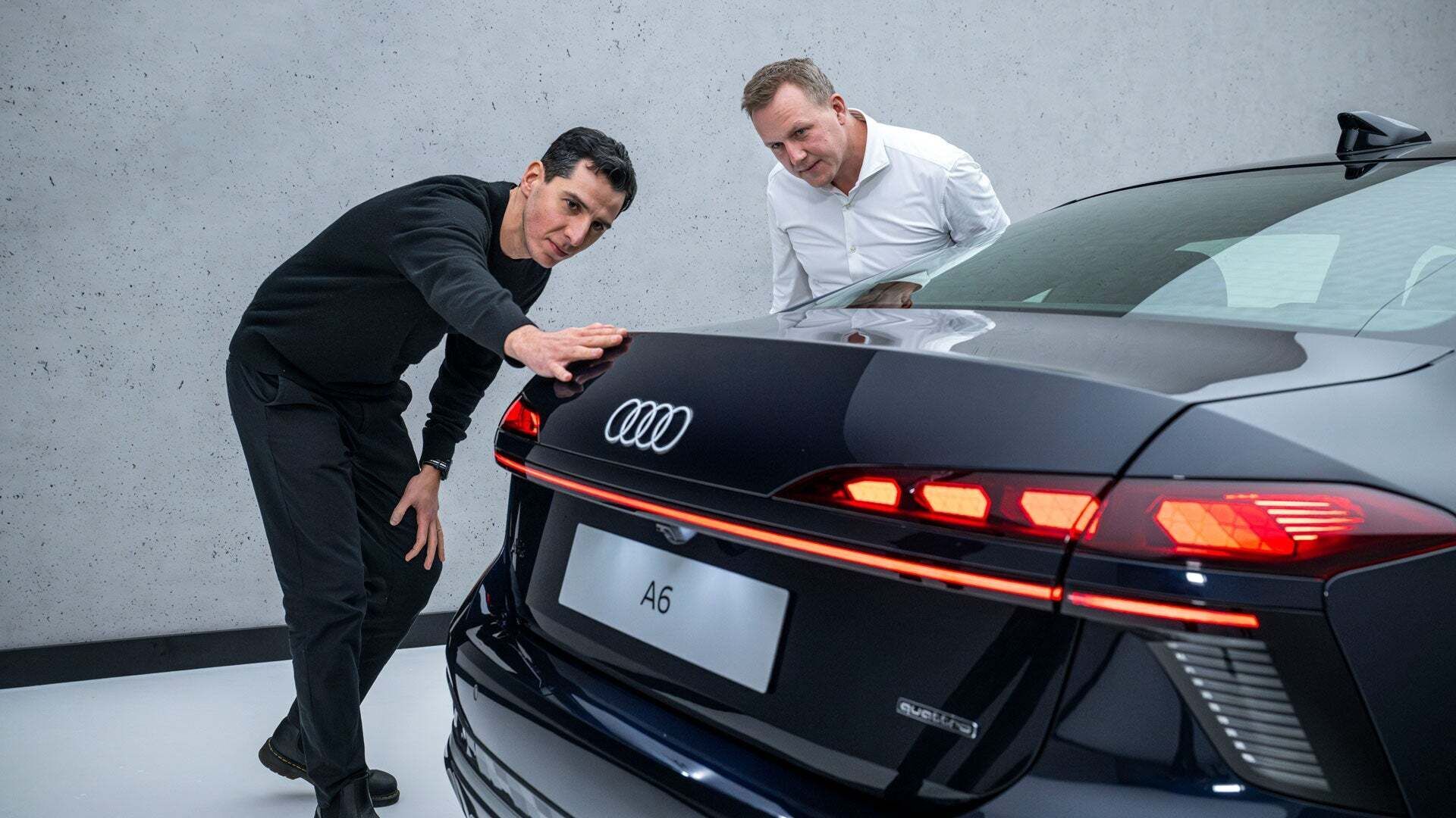 Experts in conversation. Designer Francesco d’Amore runs his hand along the rear line of the black Audi A6 Sedan, with aerodynamicist Sebastian Weiper standing next to him.