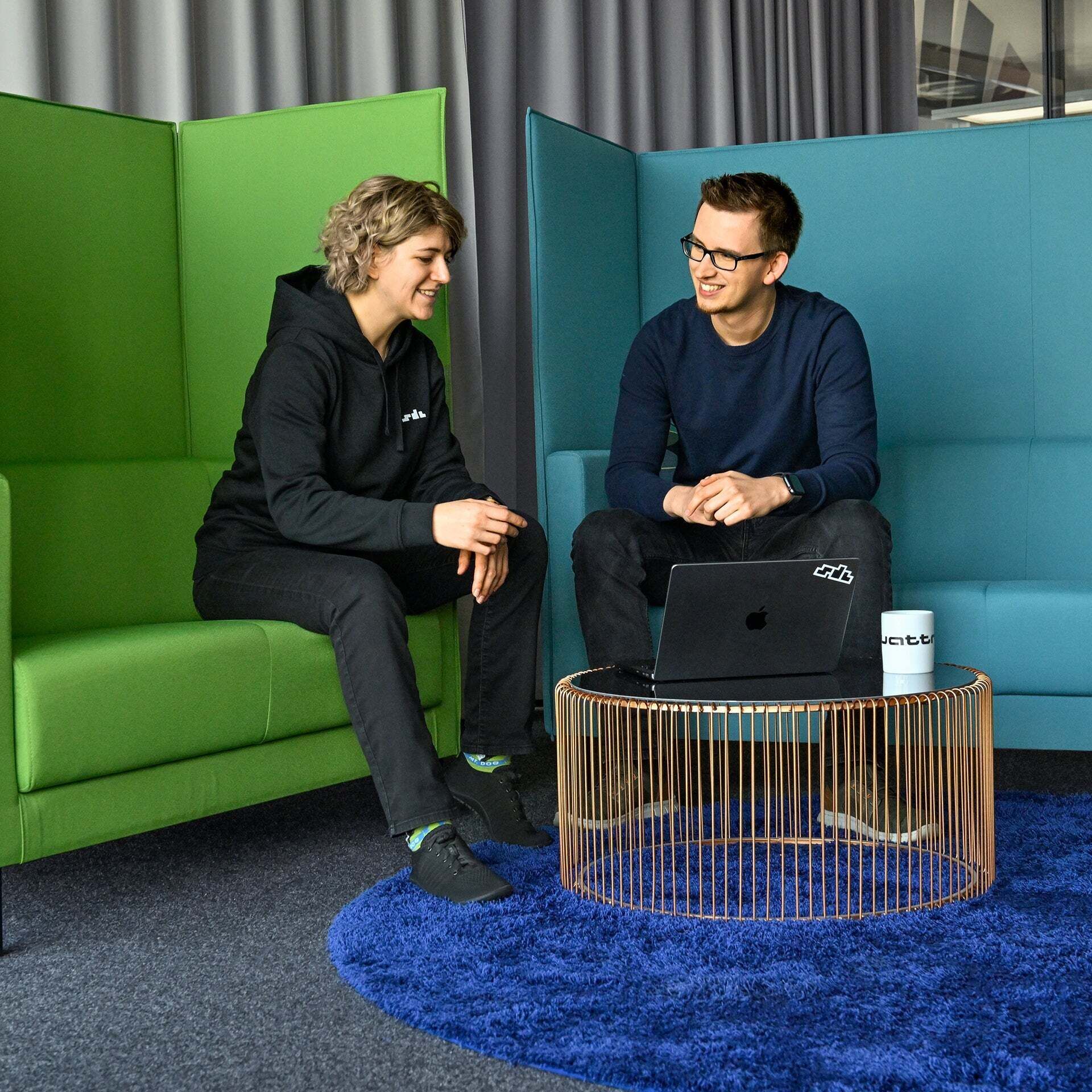 Nadine und ein Kollege vom SDC sitzen auf Bänken und sind im Gespräch - Agil arbeiten. Teamwork leben. Zukunft bewegen.
