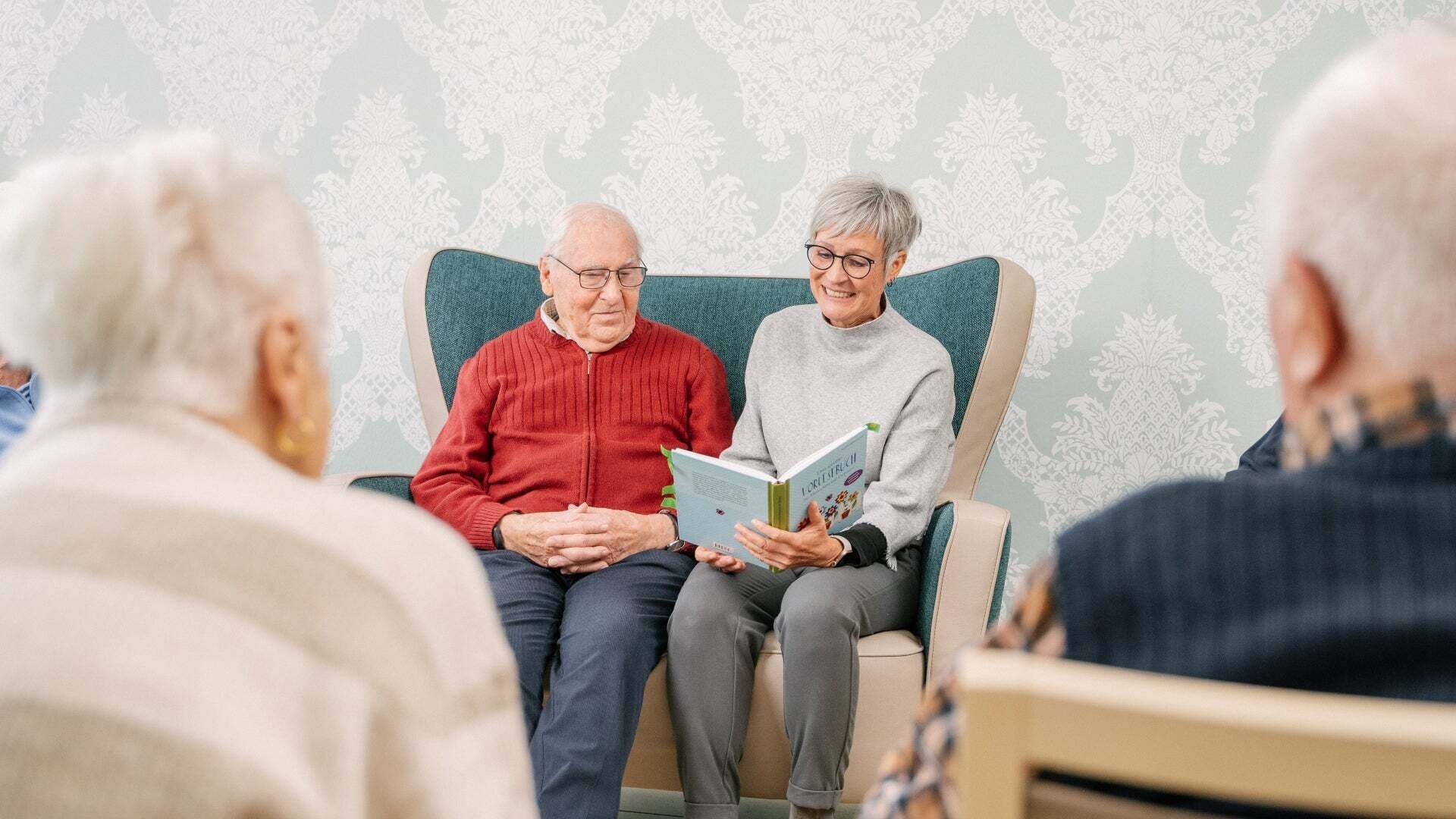 An Audi employee reads to senior citizens.