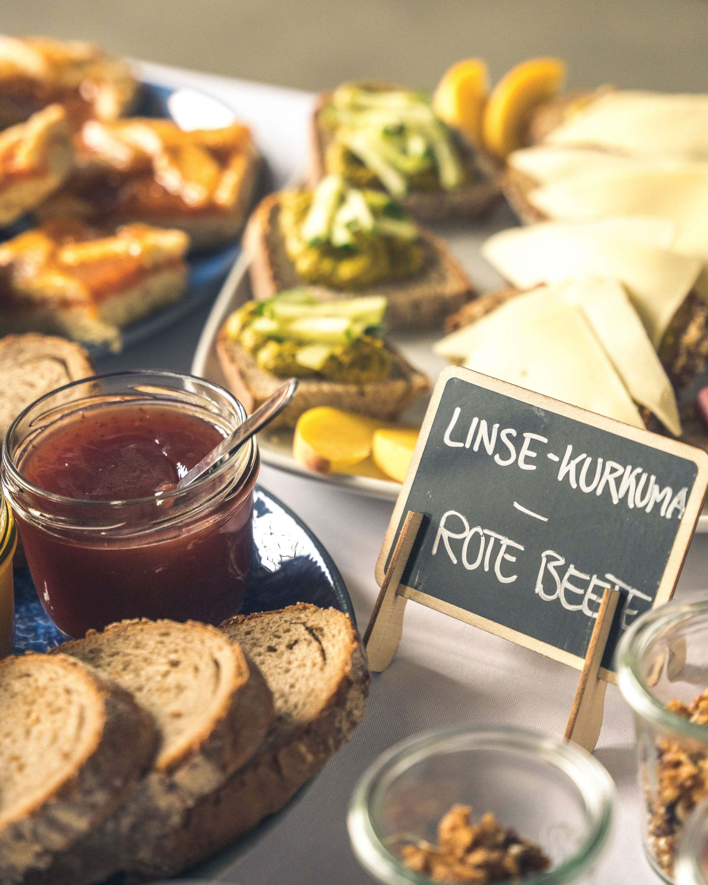 Table with sandwiches, jam, and a sign reading “Lentil and turmeric – beetroot.”