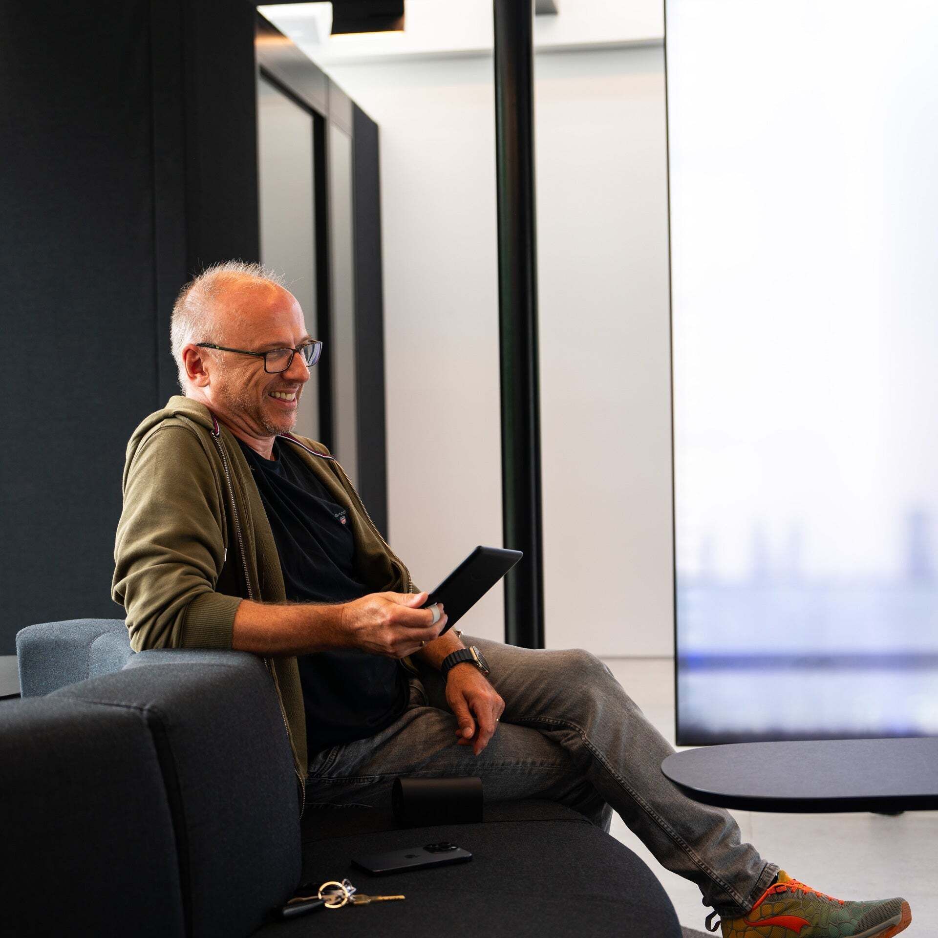 Thilo sits on a sofa with an e-reader in his hand