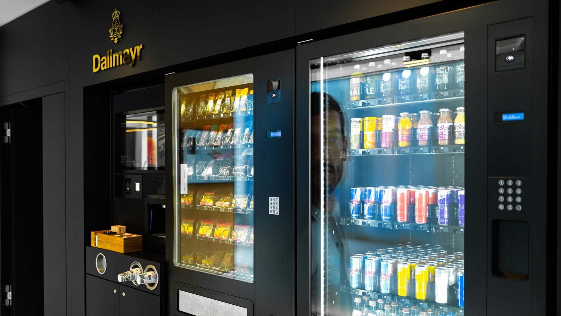A black vending machine with snacks and drinks and the golden Dallmayr logo