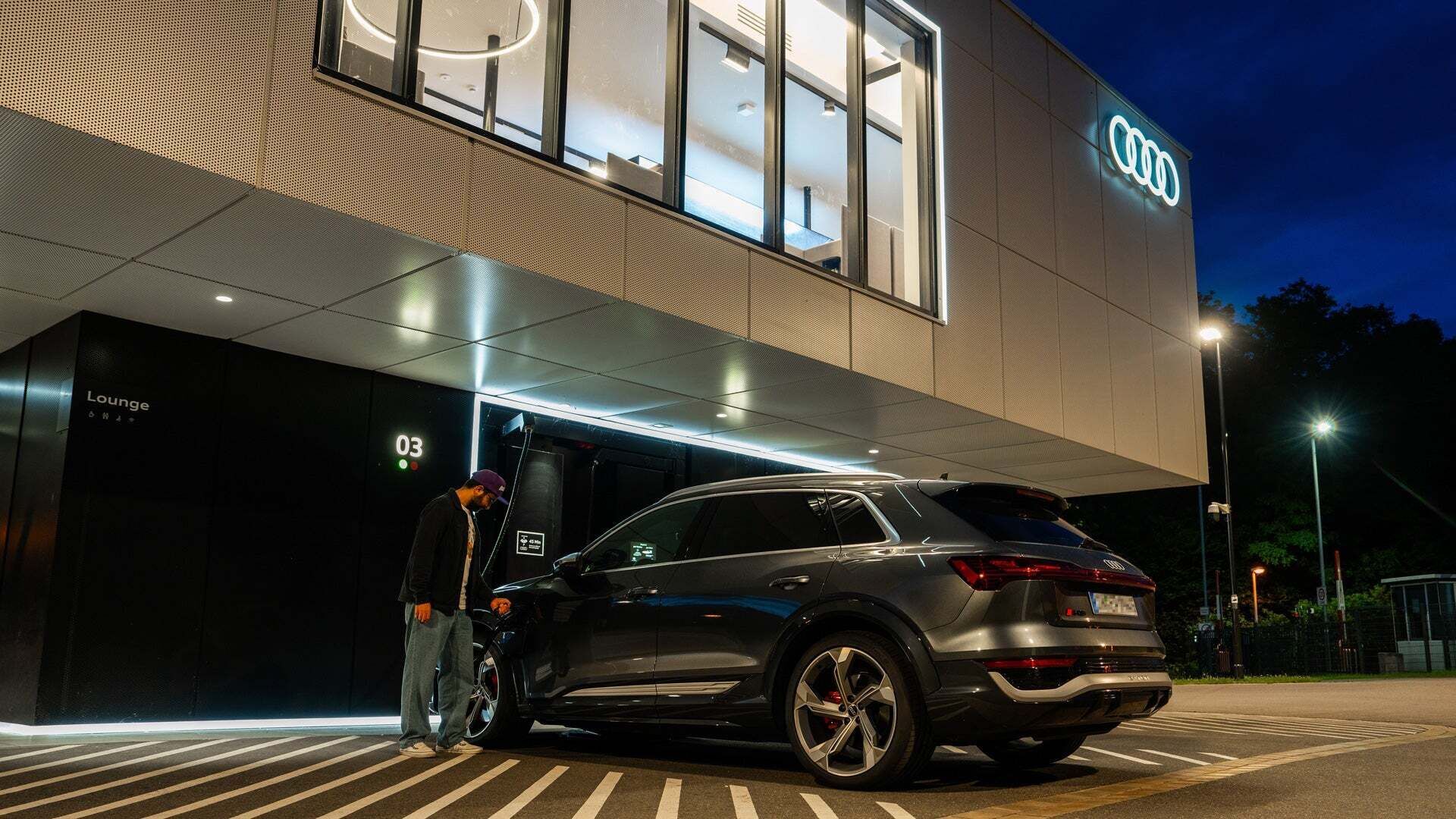 A man charges his car at the charging hub at night