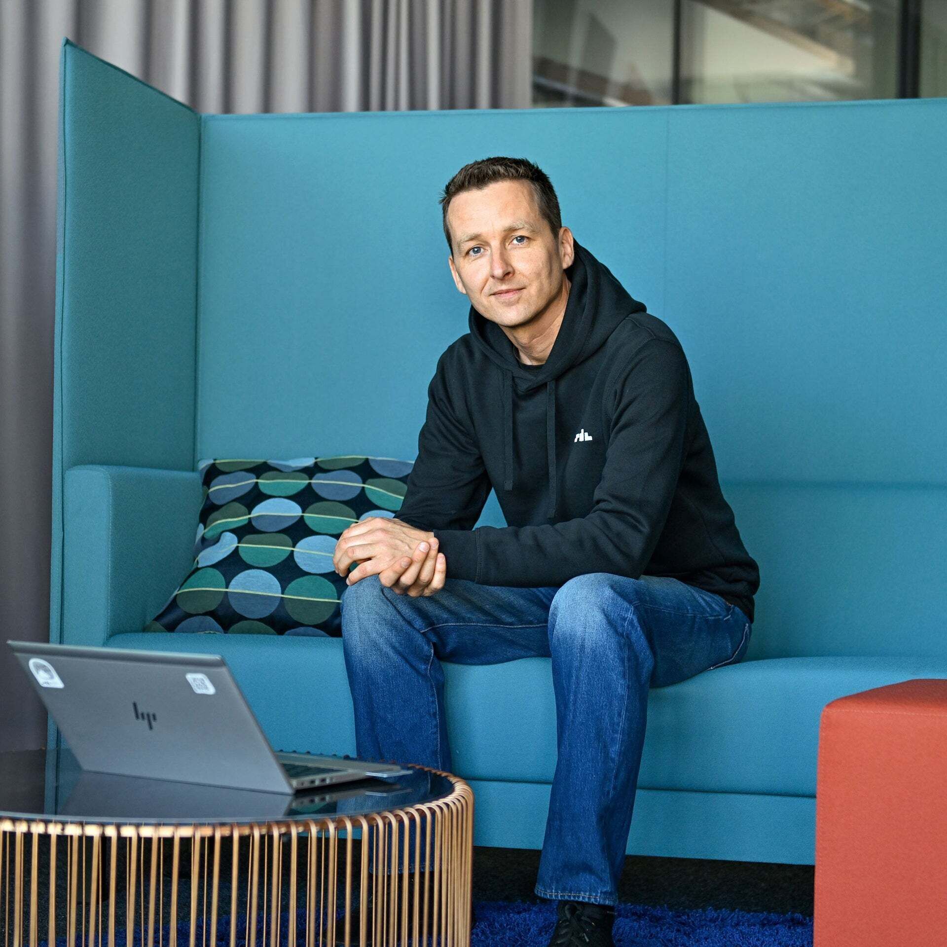 Alex, Office Lead SDC, sits on a bench and has a laptop in front of him