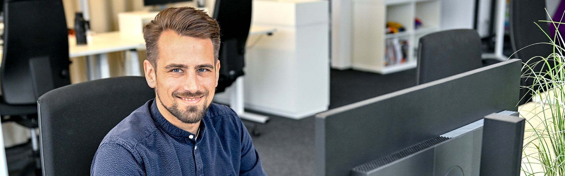 Markus, Product Manager SCD, sits at his laptop and laughs into the camera