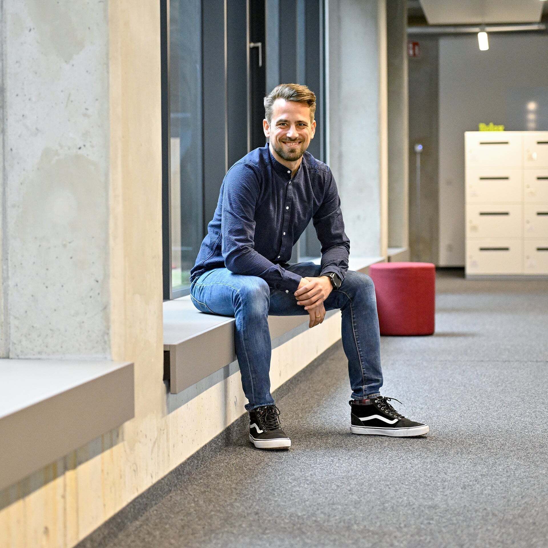 Markus, Product Manager SCD, sits on a windowsill and laughs into the camera