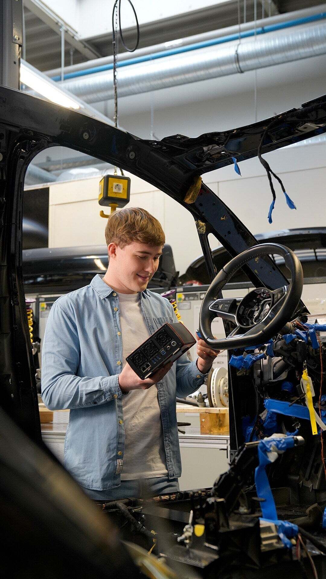 Ein Auszubildender verrichtet Arbeiten an dem Lenkrad einer Karosserie eines Autos