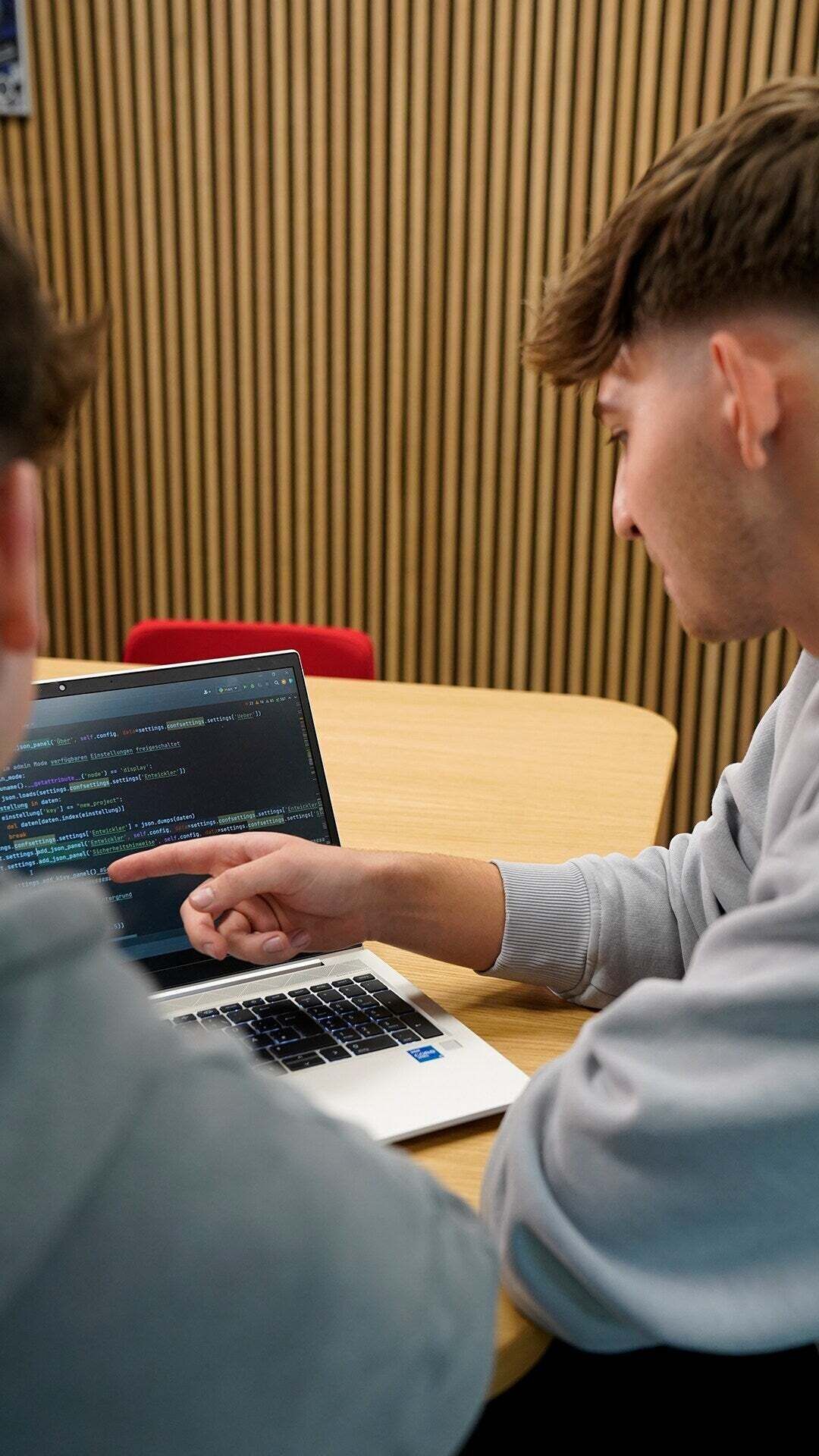 Ein Auszubildender zeigt einem anderen etwas auf einem Laptop