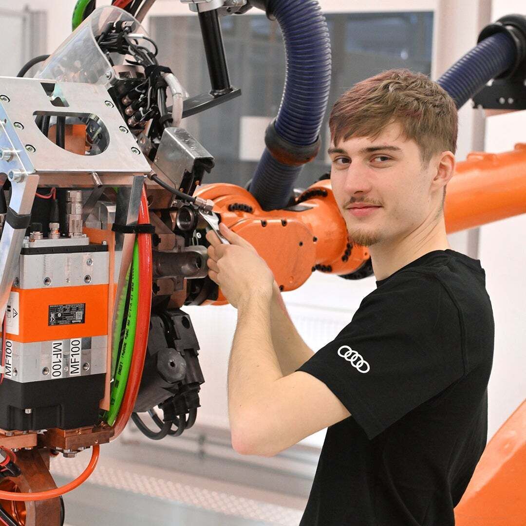 Noah schaut in die Kamera und schraubt an einer Machine herum