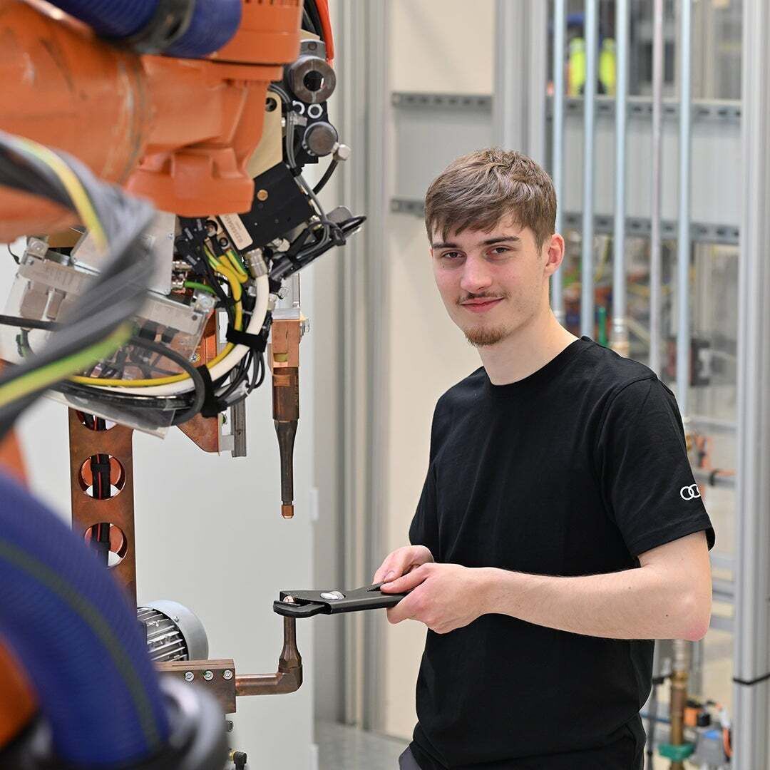 Noah schaut in die Kamera und repariert eine Maschine