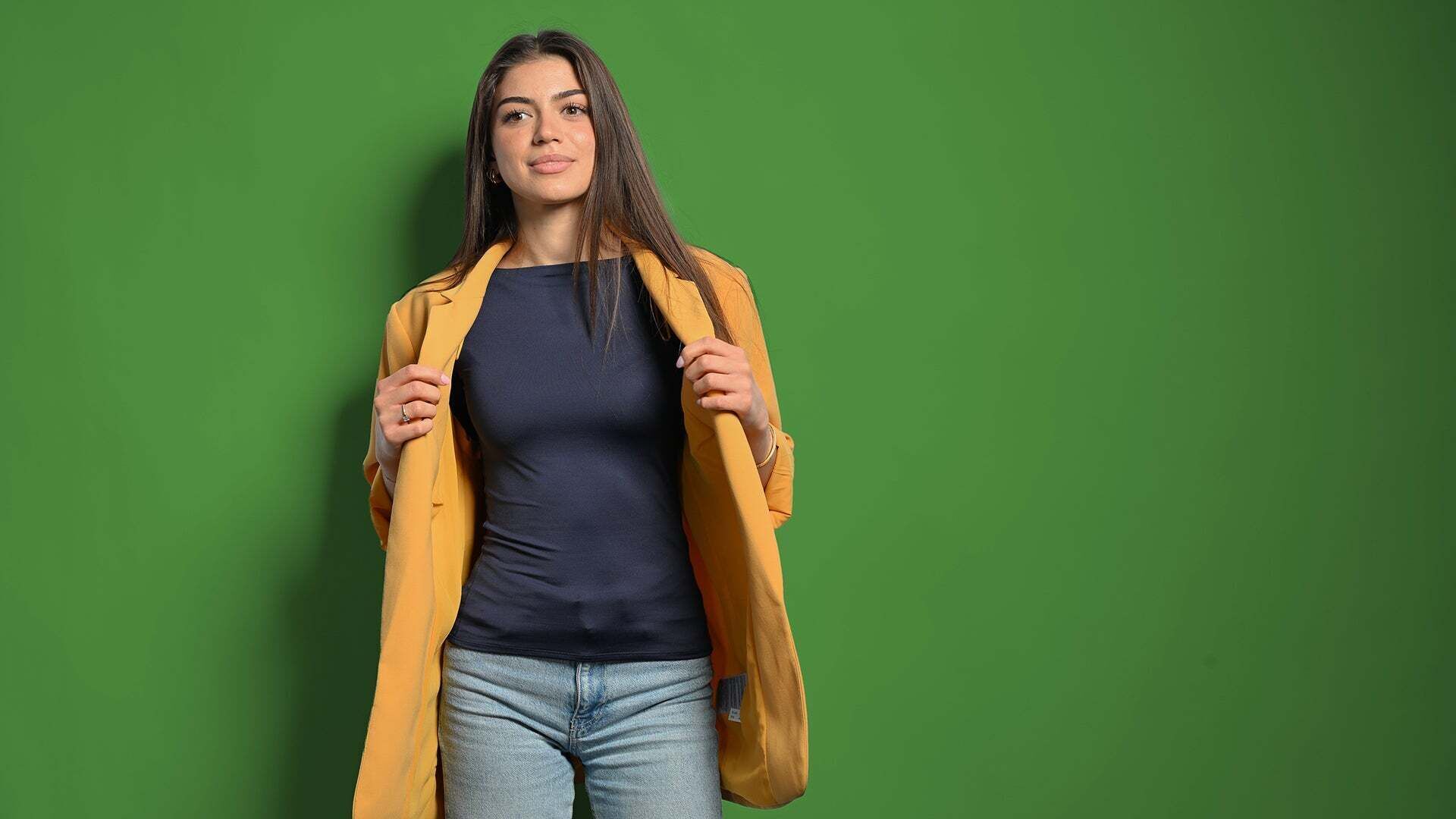 Emilia schaut in die Kamera und hält ihre Jacke
