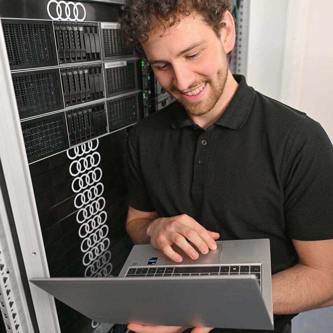 Fabian schaut auf seinen Laptop, den er in der Hand hat