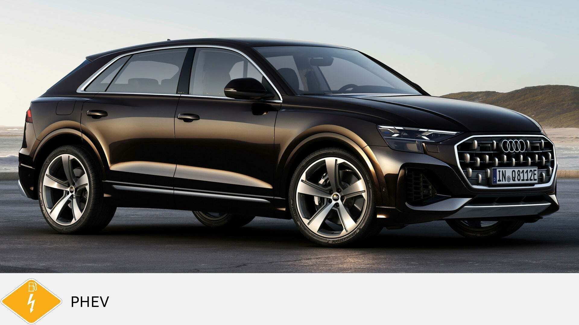 Schwarzer Audi Q8 TFSI e steht auf Asphalt an der Küste bei Tageslicht. Unten gelbes PHEV-Symbol mit Zapfsäule und Blitz.