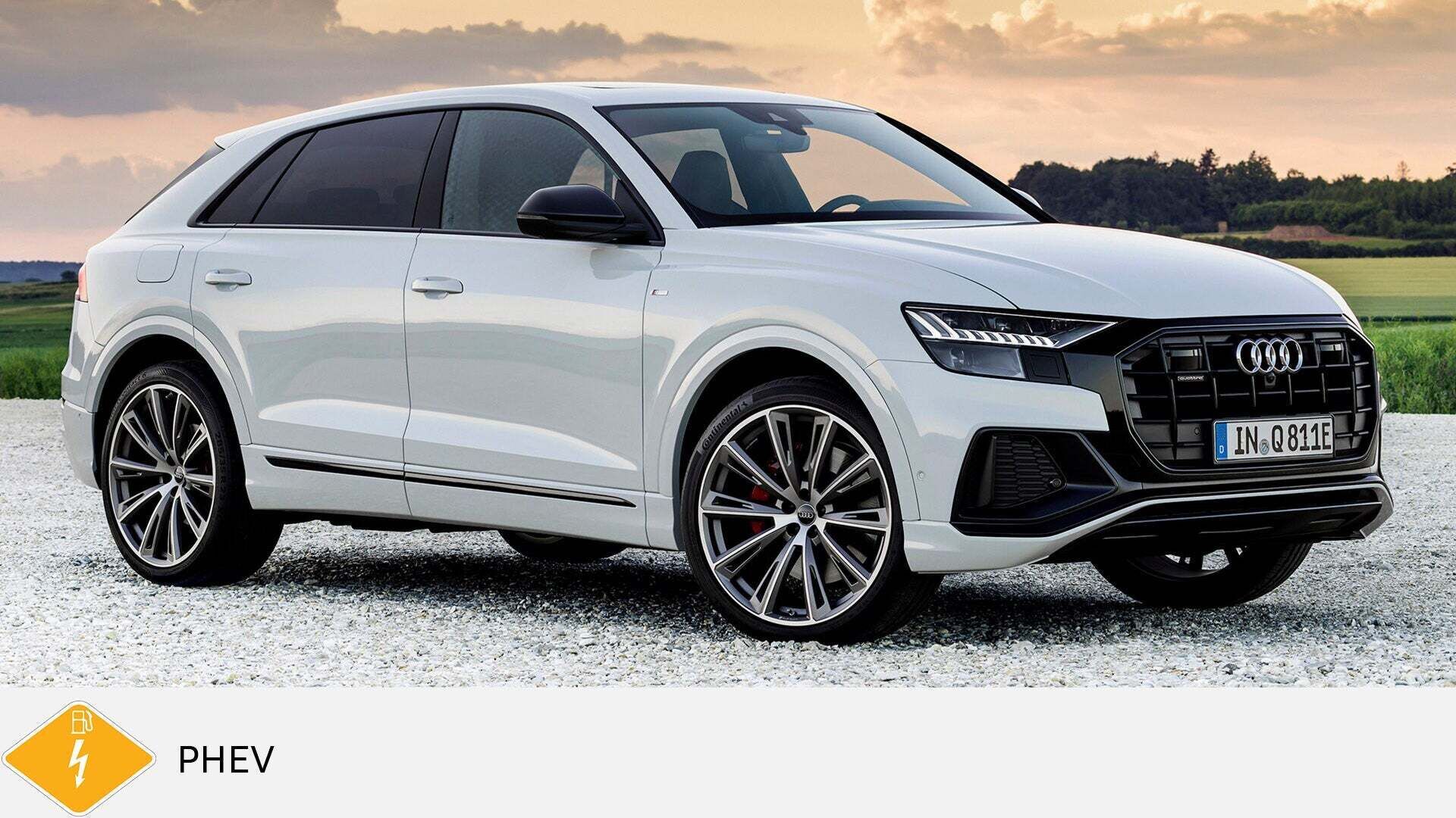 Weißer Audi Q8 TFSI e steht auf Kies vor Sonnenuntergang und Wiese. Unten gelbes PHEV-Symbol mit Zapfsäule und Blitz.