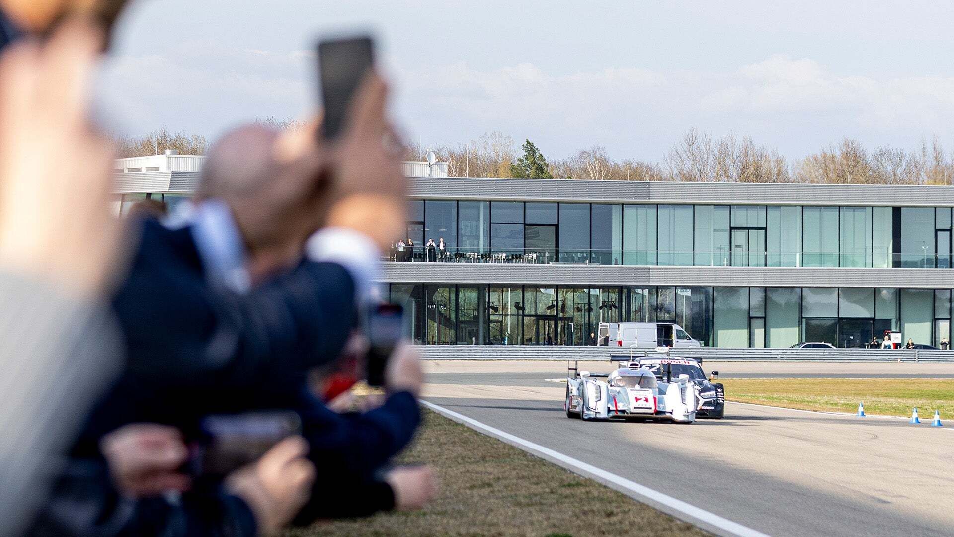 Das Foto zeigt zwei Rennwagen von Audi Sport racing legends, die auf der Rennstrecke in Neuburg vor potenziellen Kunden vorgeführt werden.