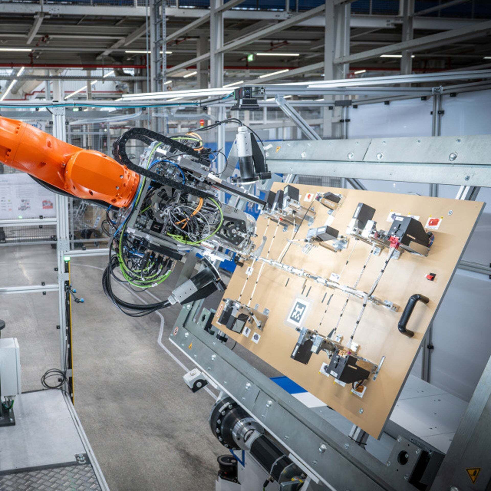 A robotic arm performing automated taping of a wiring harness in a production hall at the Ingolstadt plant.