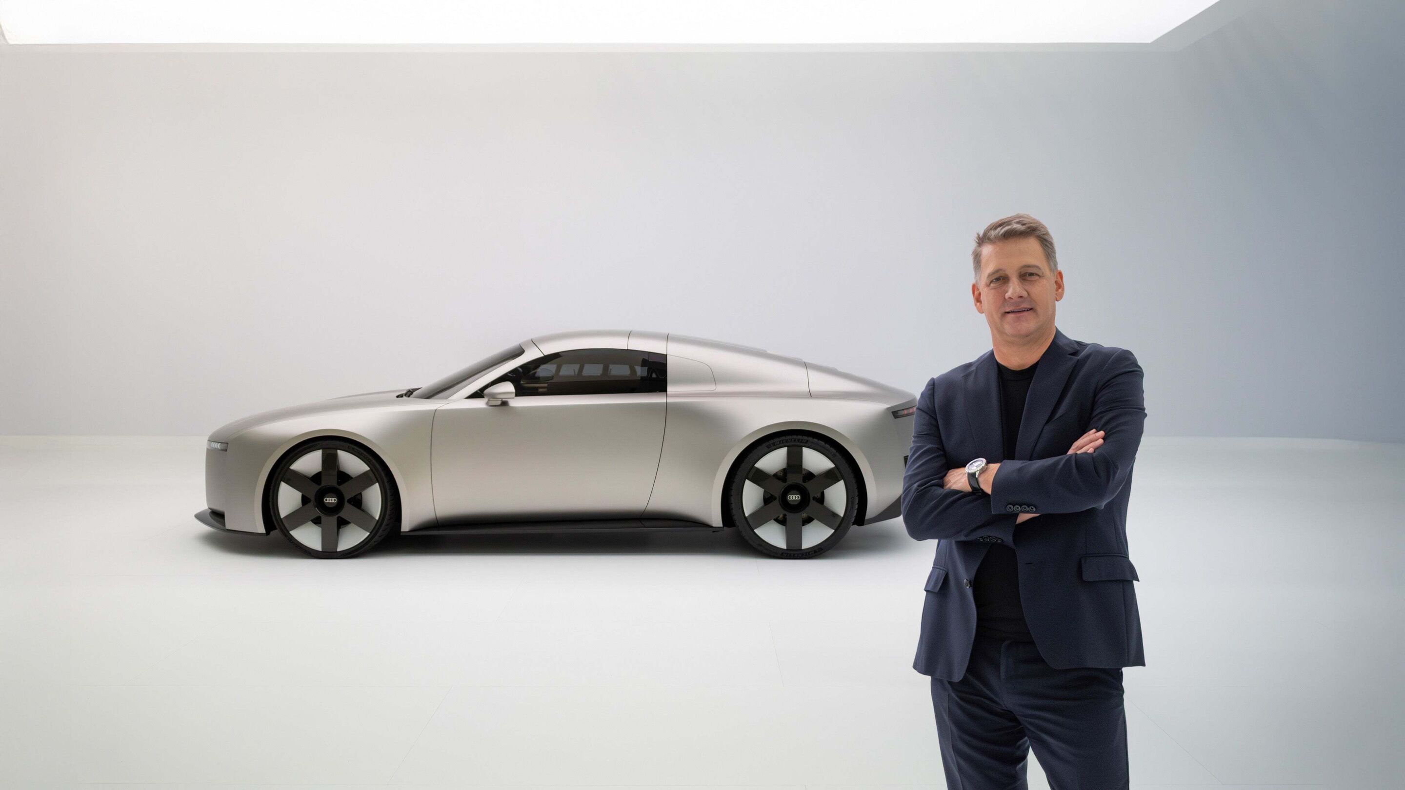 Audi CEO Gernot Döllner stands right besides the Audi Concept C in front of a white wall in a clean studio.
