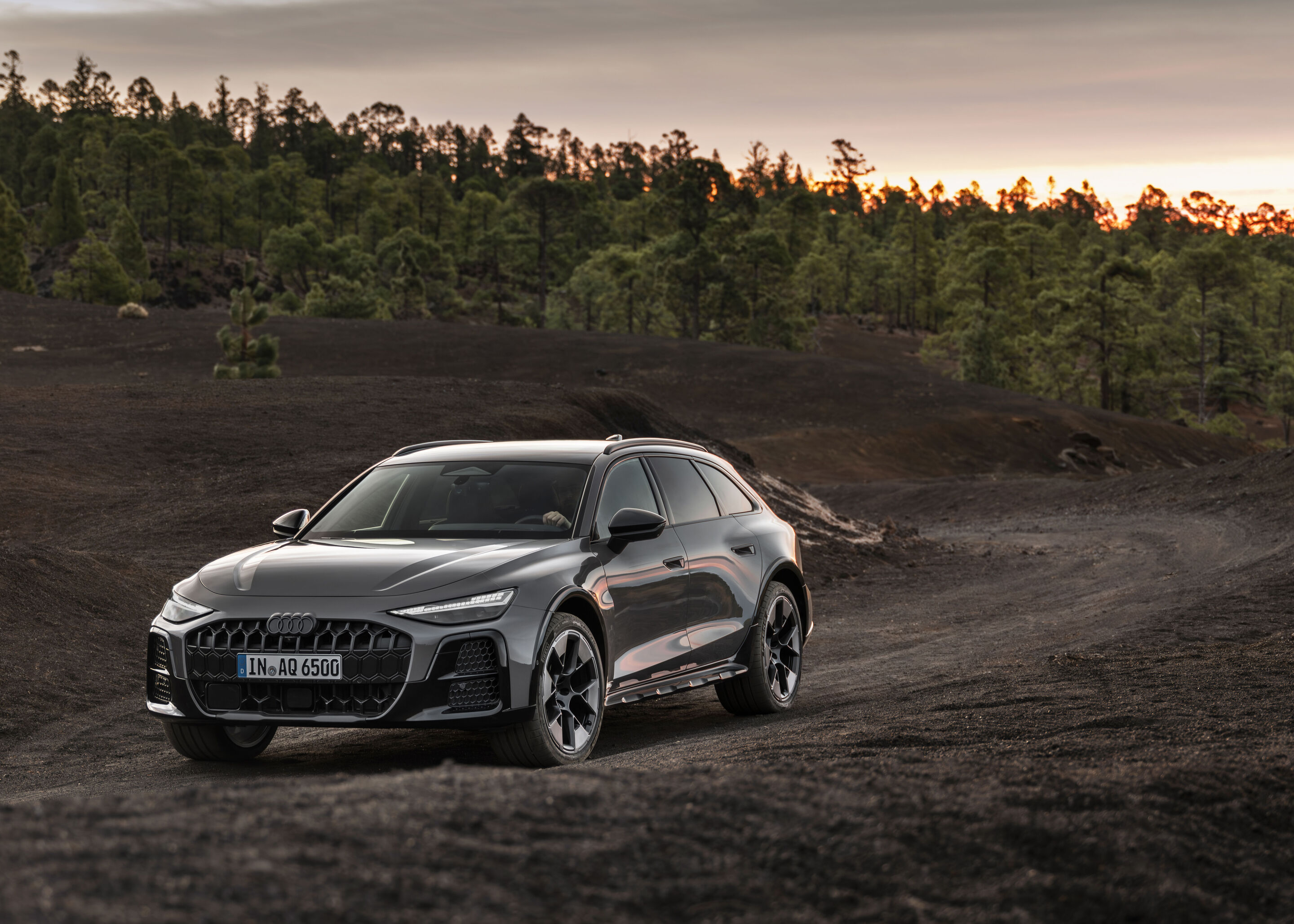 Audi A6 allroad quattro - Audi A6 allroad (plateaugrau metallic) in Dreiviertel-Frontansicht auf unbefestigtem Untergrund bei einsetzendem Abendlicht.