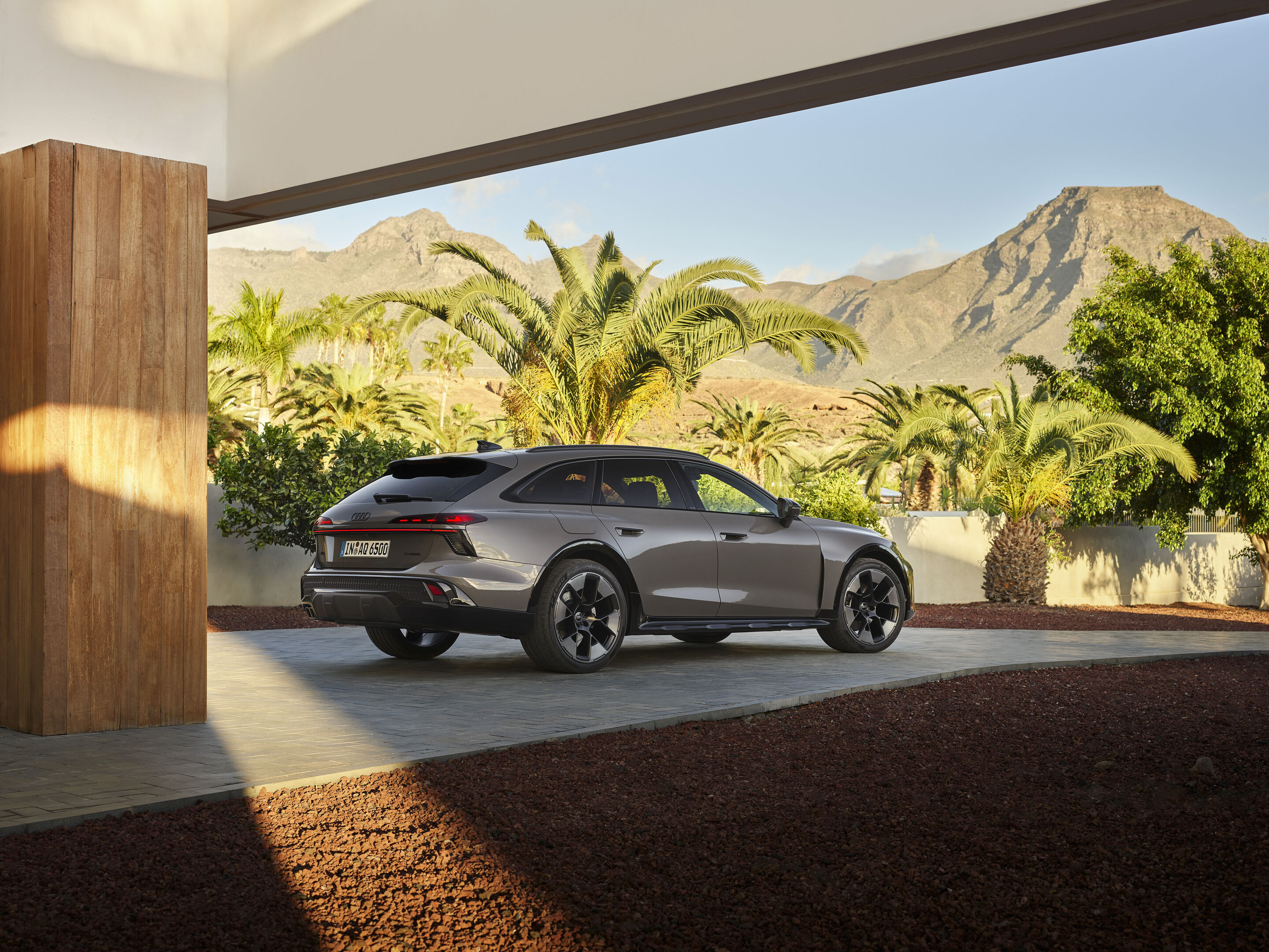 Audi A6 allroad quattro - Standaufnahme in Dreiviertel-Heckansicht des Audi A6 allroad (plateaugrau metallic) in moderner Architektur und vor markantem Bergpanorama (Standaufnahme).