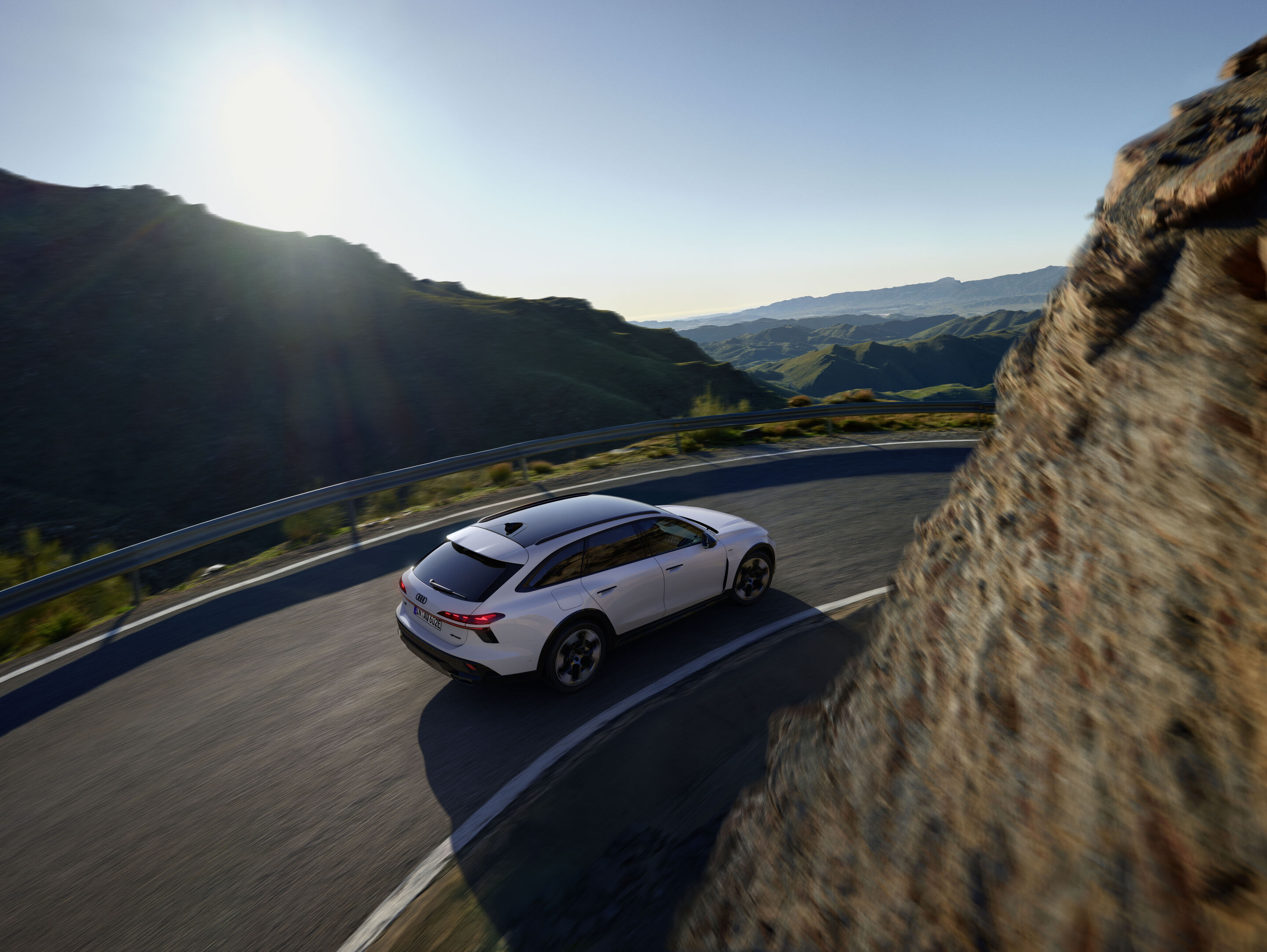 Audi A6 allroad e-hybrid quattro - Dynamische Aufnahme: Audi A6 allroad e-hybrid (gletscherweiß) auf kurvenreicher Bergstraße mit weitem Blick über die Landschaft.