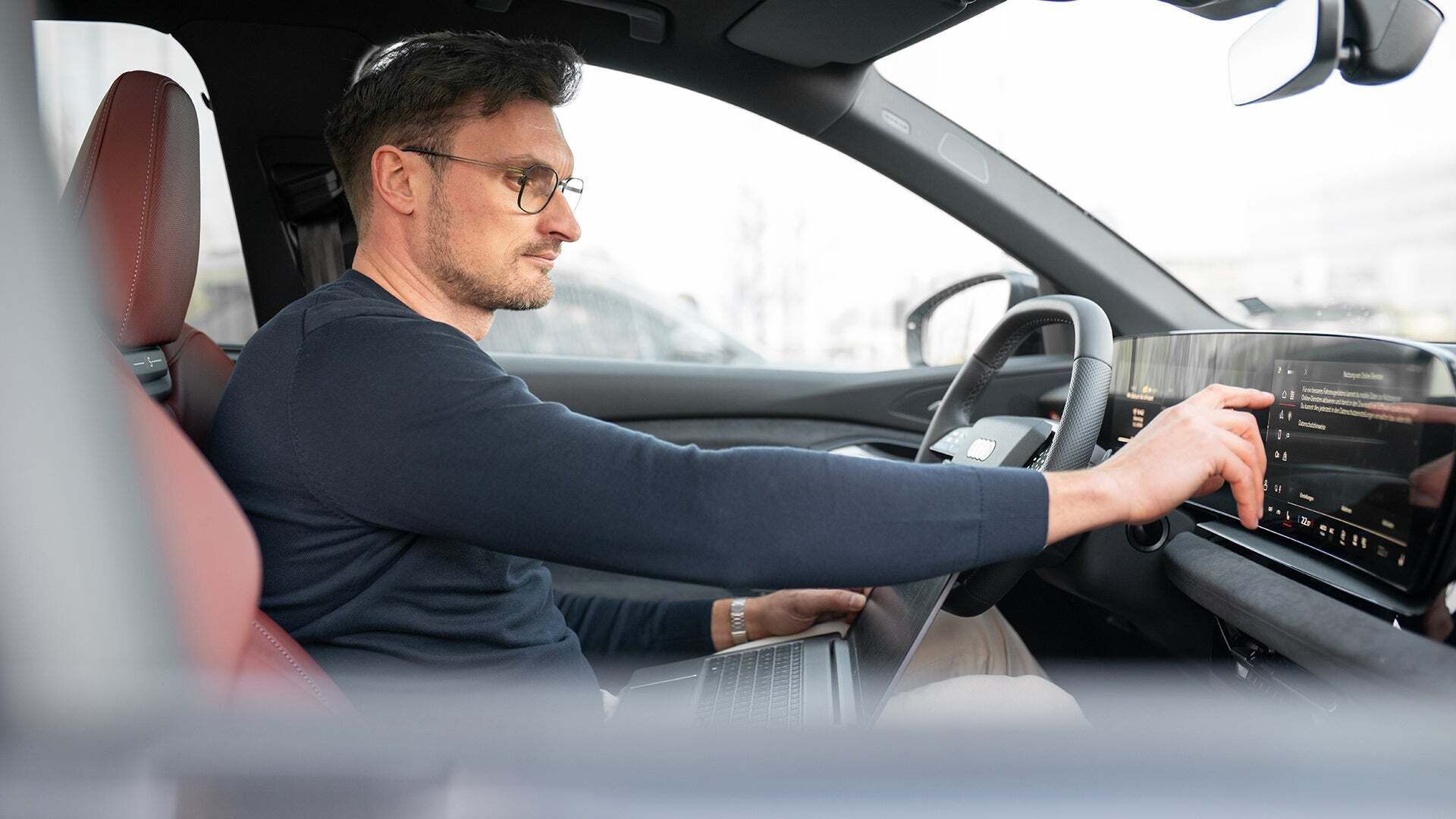 Alexander sitzt im Auto und hat eine Hand am MMI-Display