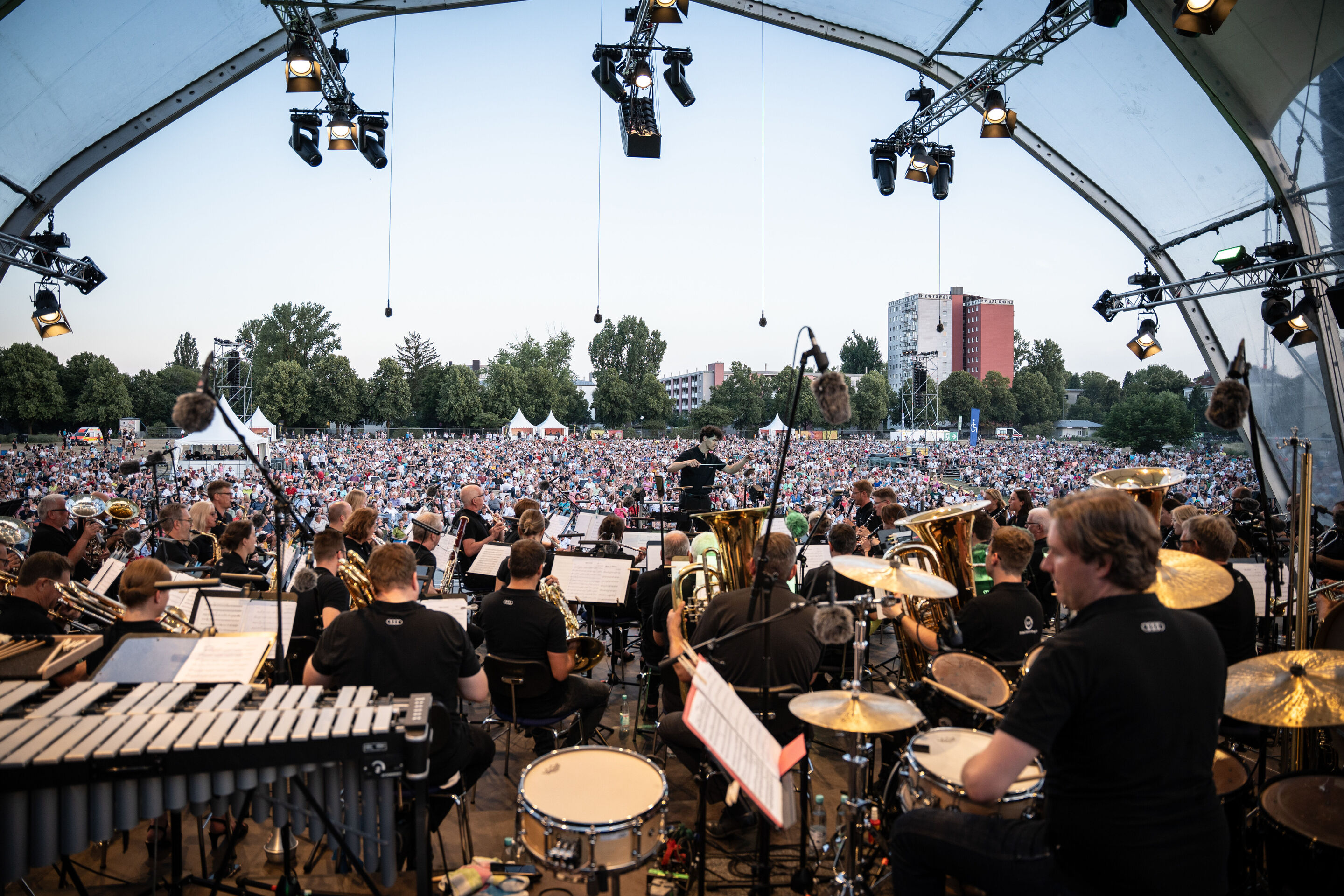 Die Audi Bläserphilharmonie beim Eröffnungskonzert/Klassik Open Air im Klenzepark - Blick von der Bühne über die Audi Bläserphilharmonie auf die rund 6.000 Besucherinnen und Besucher beim Klassik Open Air 2026 im Klenzepark. Das Orchester spielt unter...