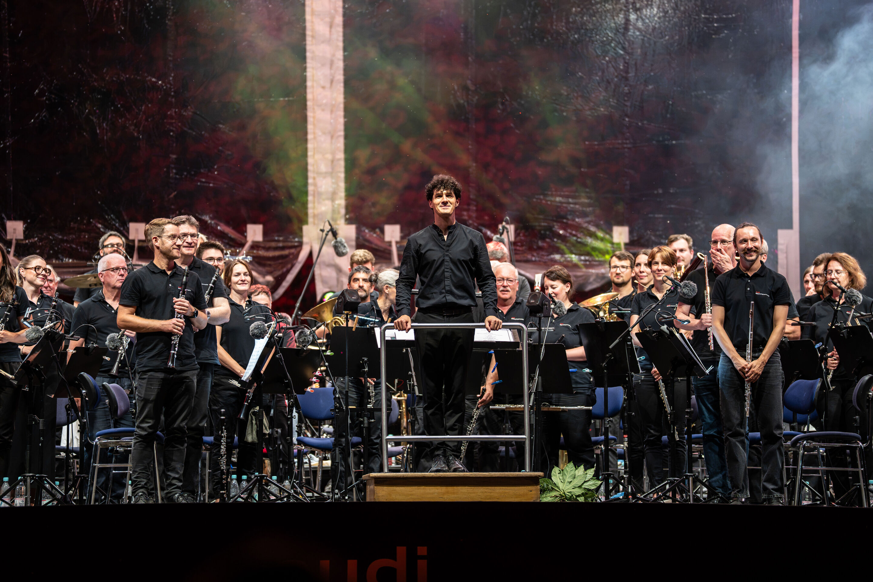 Die Audi Bläserphilharmonie beim Eröffnungskonzert/Klassik Open Air im Klenzepark - Auf der Bühne des Klassik Open Airs im Klenzepark 2026 steht Dirigent Mathias Wehr auf dem Dirigentenpodest, umgeben von den Musikerinnen und Musikern der Audi Bläserphilharmonie,...