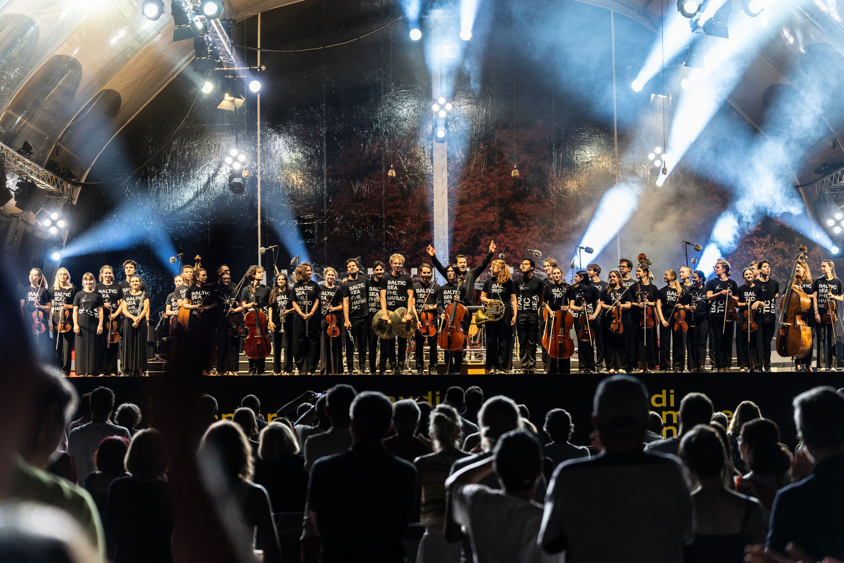 Baltic Sea Philharmonic beim Klassik Open Air im Klenzepark - Blick aus dem Publikum auf die Bühne des Klassik Open-Airs im Klenzepark 2026: Die Musikerinnen und Musiker des Baltic Sea Philharmonic stehen zum Schlussapplaus vor dem Orchester, während...