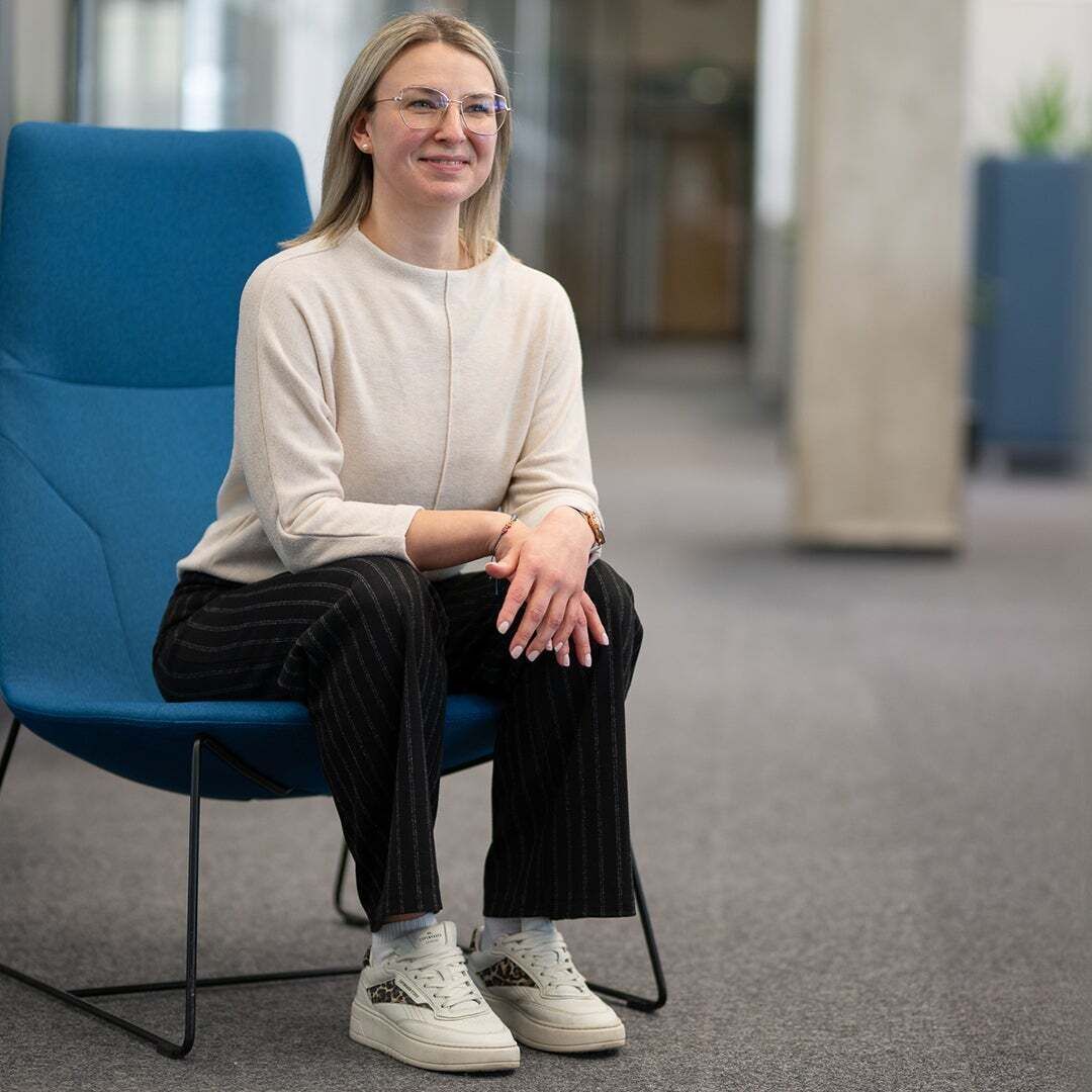 Raphaela Fritz - Raphaela sitzt auf einem Stuhl und lächelt an die Kamera vorbei