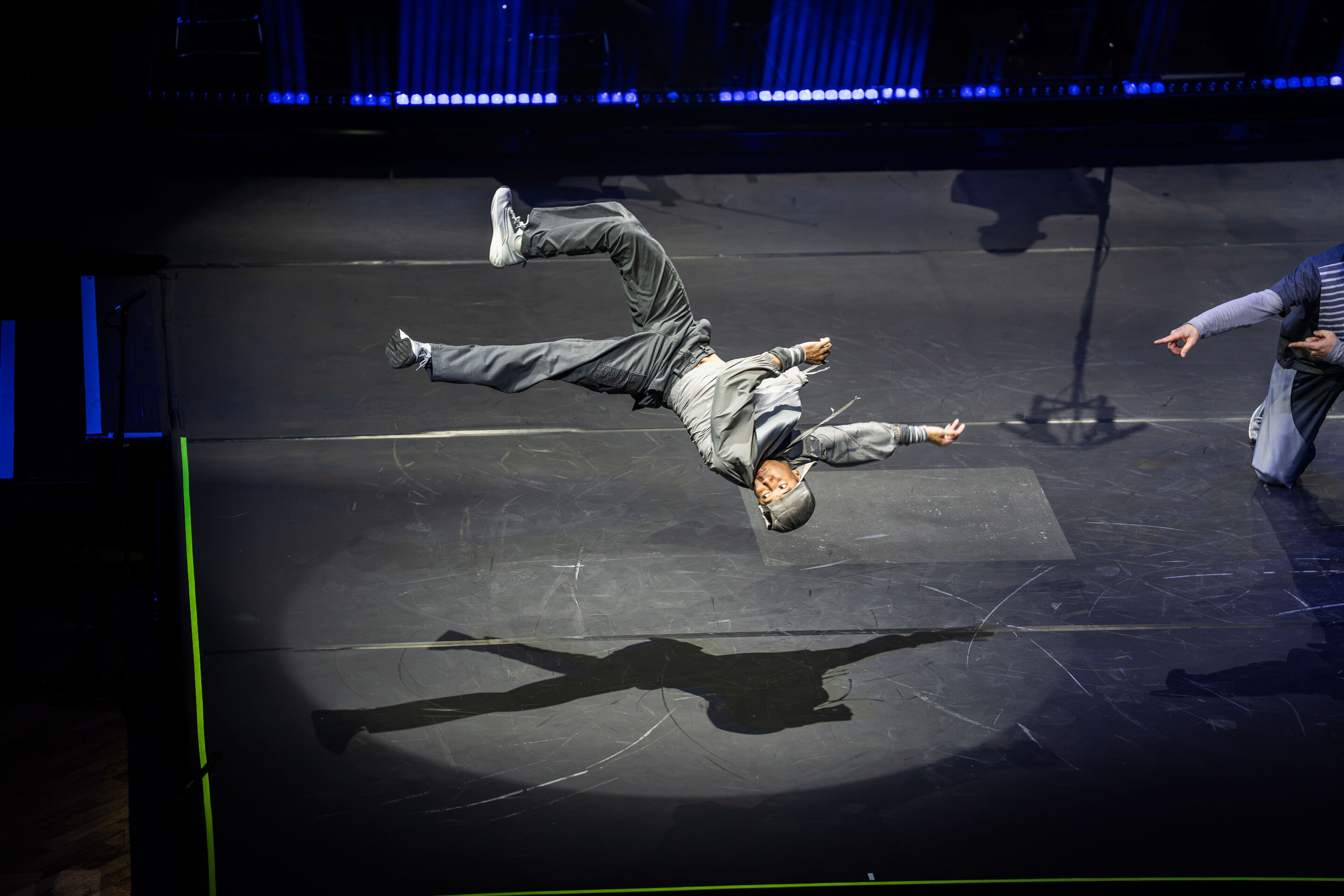 Audi Summer concert: Performance of “Dido and Aeneas” featuring Flying Steps at the Festsaal Ingolstadt - On the illuminated stage, a dancer from the Flying Steps dance company can be seen wearing a grey costume with a hood and light-coloured trainers....