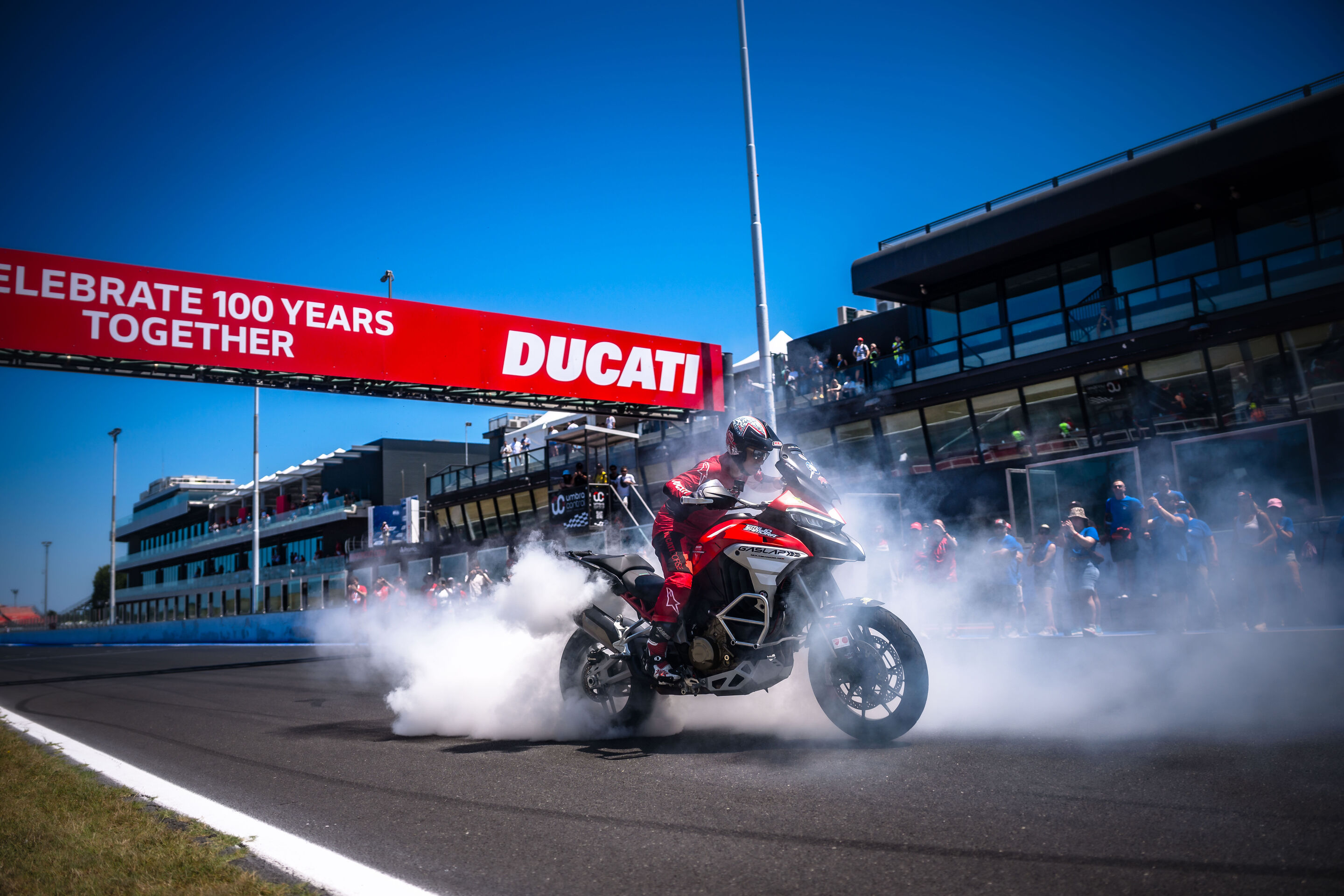 Ducati feiert 100 Jahre Unternehmensgeschichte - Ein Fahrer oder eine Fahrerin setzt auf einer Ducati Multistrada V4 bei einer Fahrdemonstration am Misano World Circuit eindrucksvolle Akzente