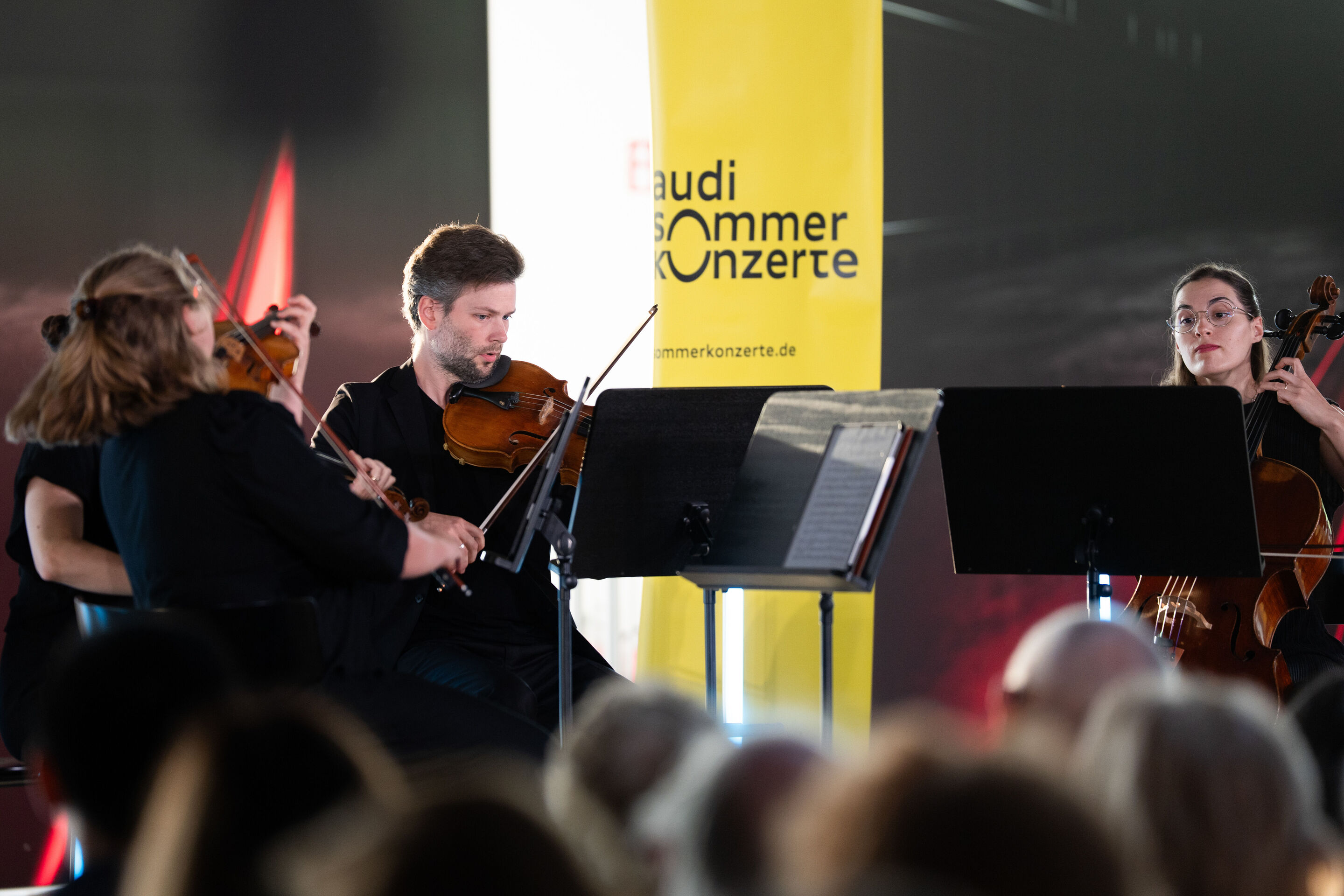 Audi Summer concert: Barbican Quartet at Audi museum mobile - View from the audience of the Barbican Quartet performing at the museum mobile of the Audi Forum Ingolstadt. The ensemble members play their string instruments in front of their music stands,...