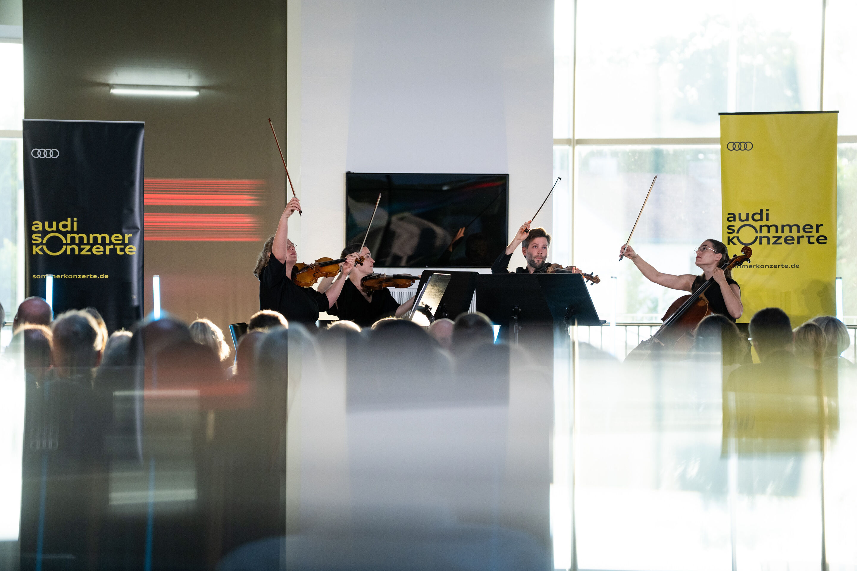 Audi Summer concert: Barbican Quartet at Audi museum mobile - View from the audience of the Barbican Quartet performing at the museum mobile of the Audi Forum Ingolstadt. The four ensemble members play their string instruments in front of their music...