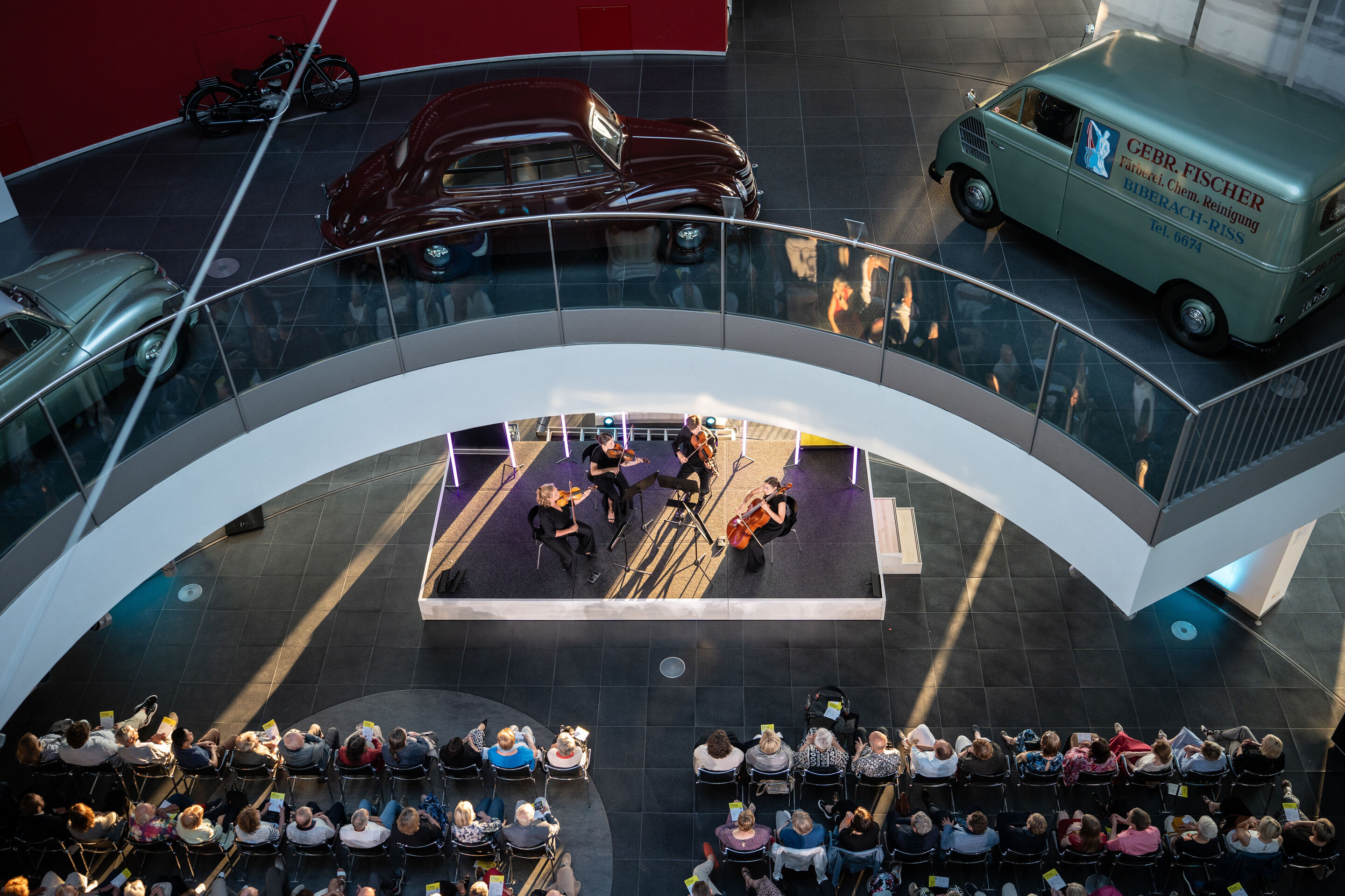 Audi Summer concert: Barbican Quartet at Audi museum mobile - View from an elevated position of the Barbican Quartet concert at the museum mobile of the Audi Forum Ingolstadt. The four musicians perform on stage while the audience watches from the seating...