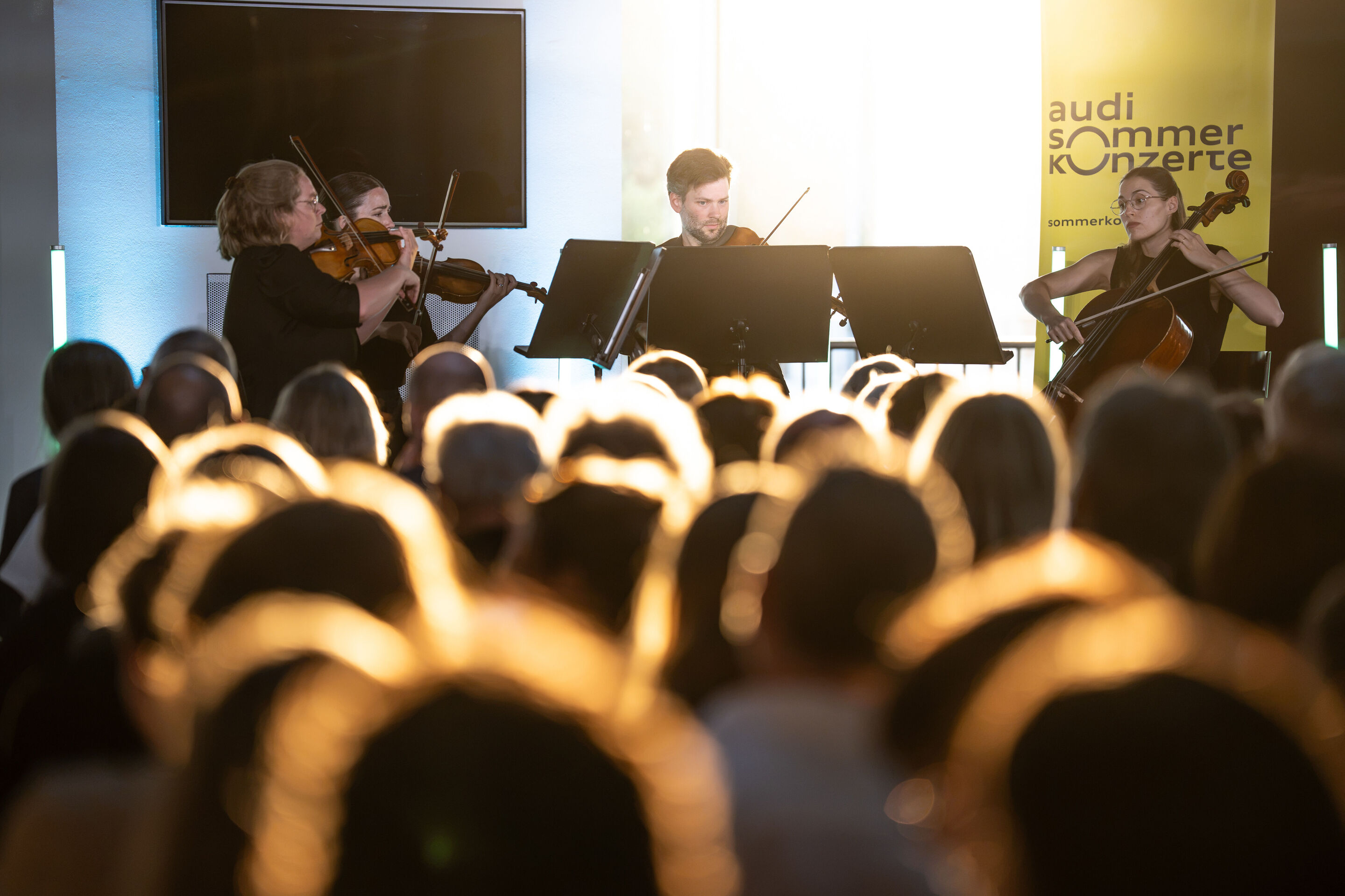 Audi Summer concert: Barbican Quartet at Audi museum mobile - View from the audience of the Barbican Quartet performing at the museum mobile of the Audi Forum Ingolstadt. The four ensemble members play their string instruments in front of their music...