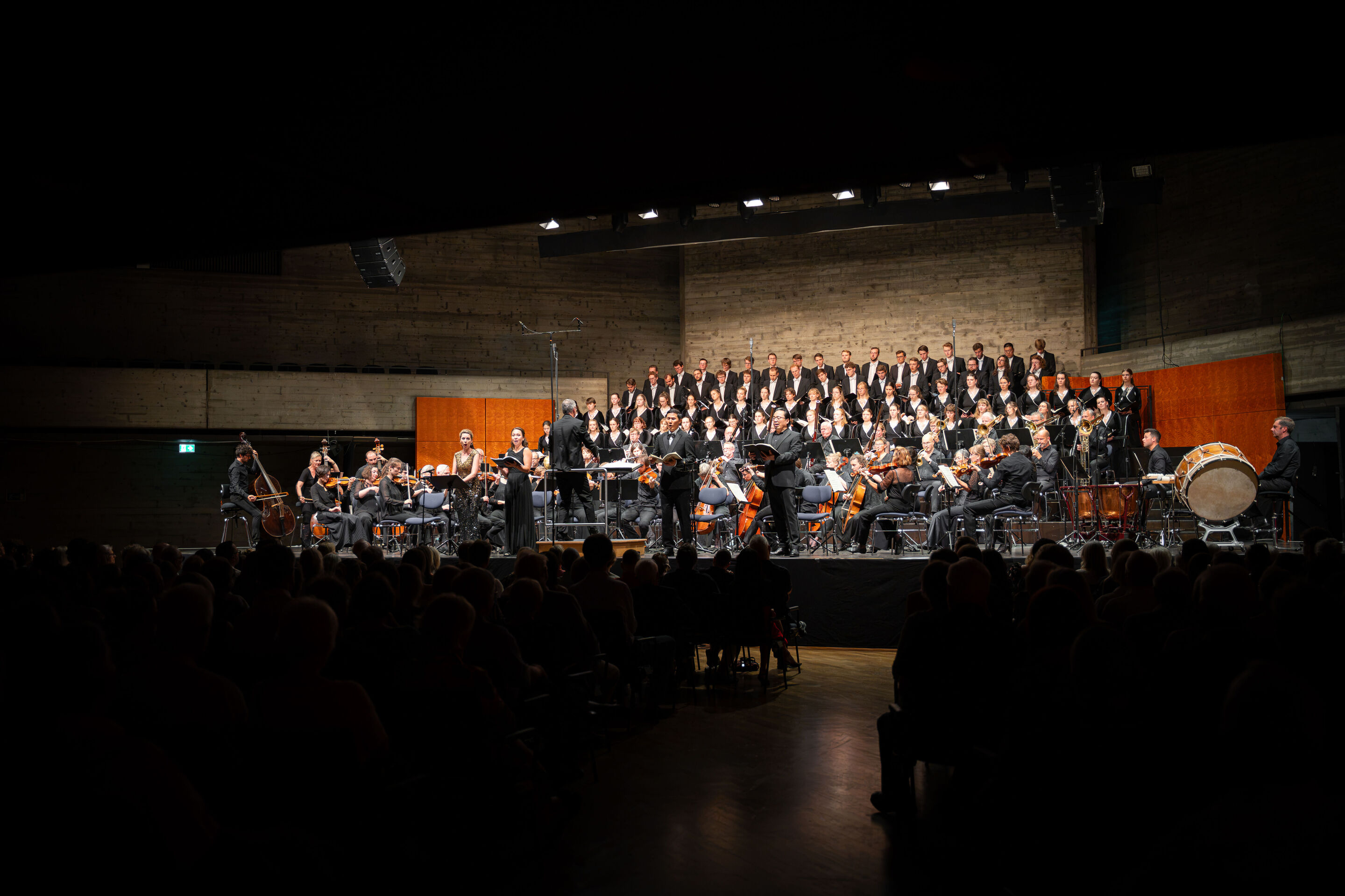 Audi Summer Concerts 2026: Closing concert - View from the audience of the stage in the Festsaal Ingolstadt. The Audi Youth Choir Academy stands on tiered choir risers behind the Akademie für Alte Musik Berlin. Martin Steidler conducts the performance...