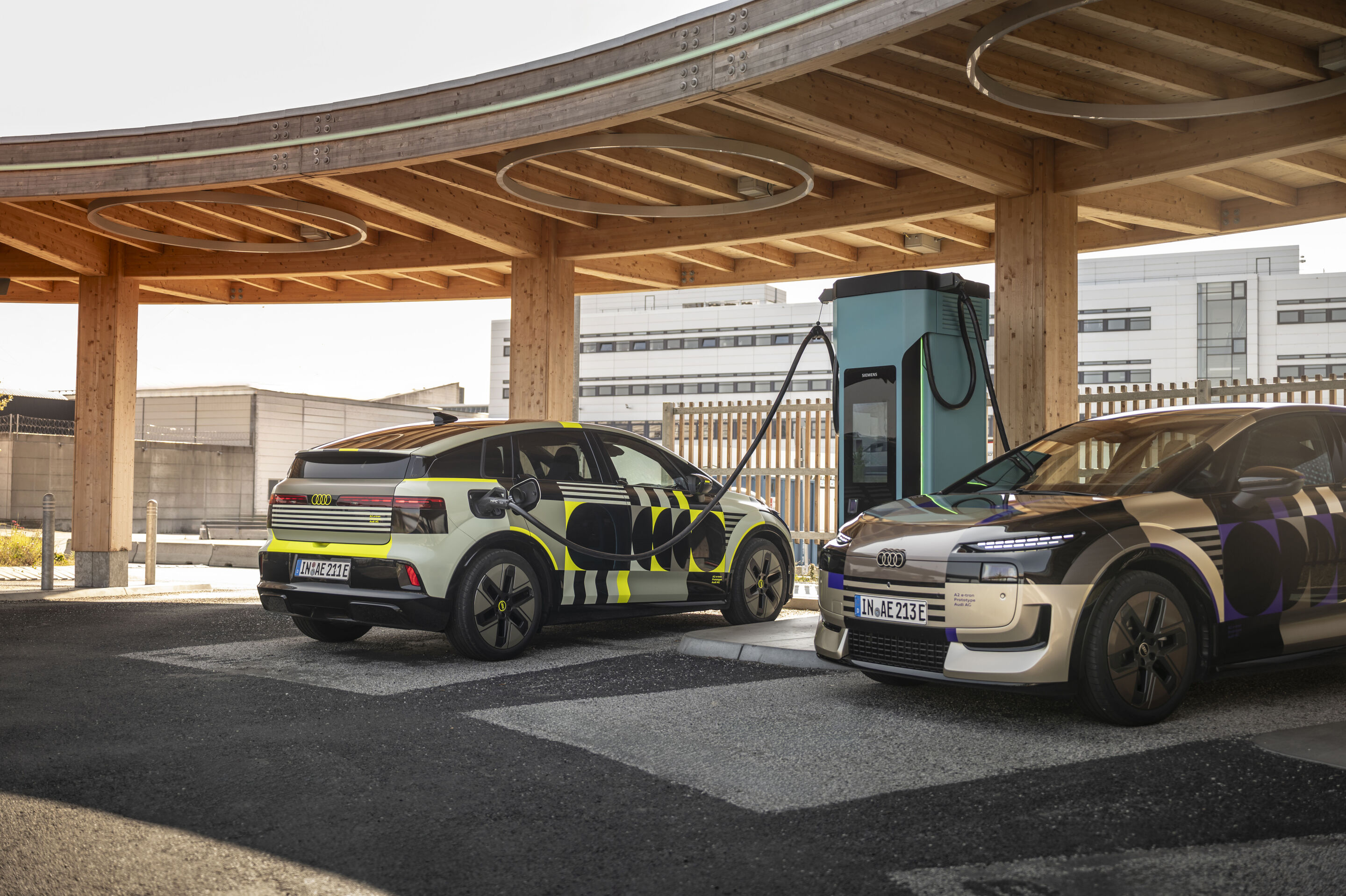 Audi A2 e-tron with design livery - Outdoor shot of two Audi A2 e-tron vehicles at a charging station.