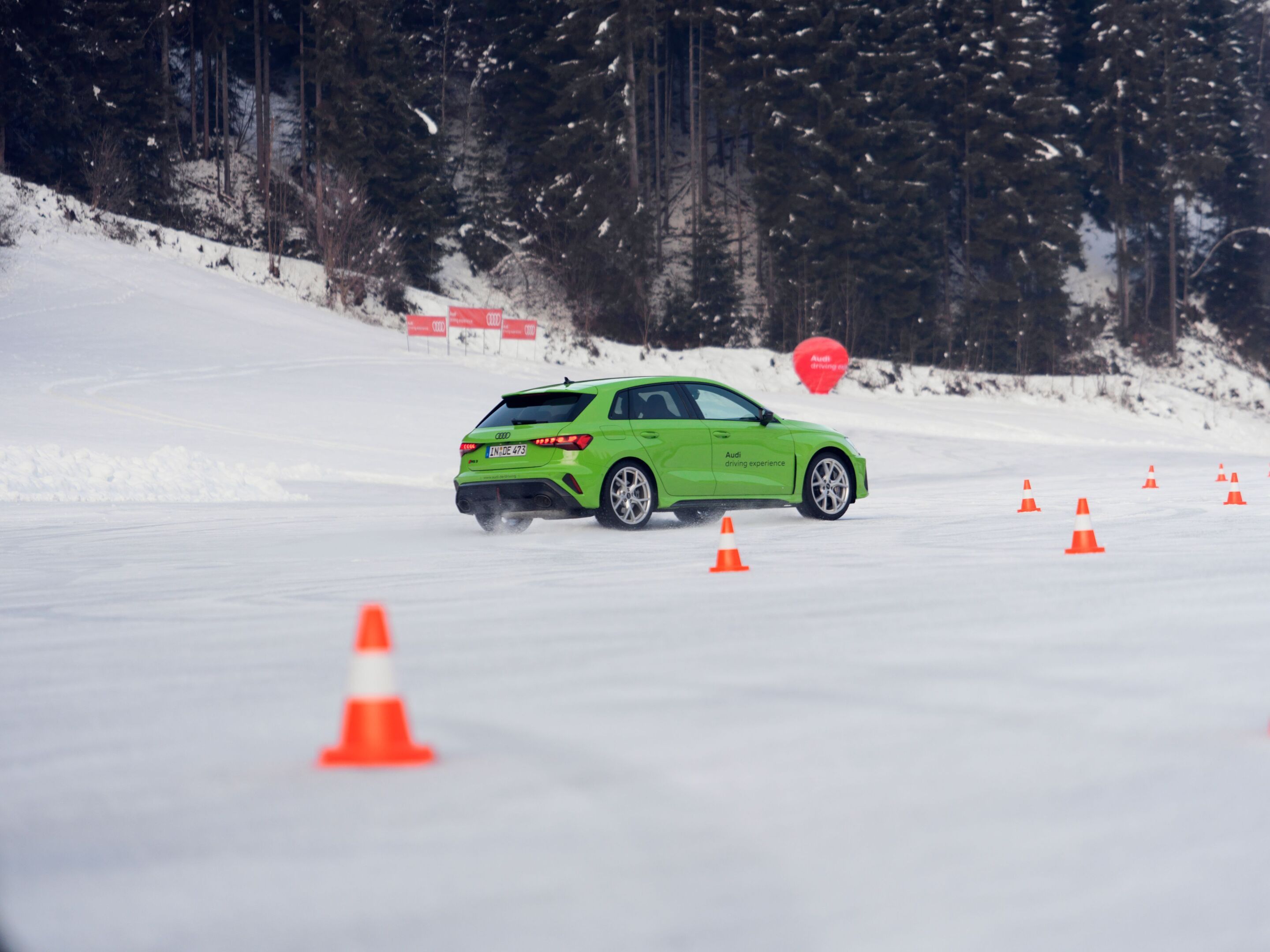 Audi driving experience - Audi RS 3 Sportback in Kyalami Green on a snow and ice course during an Audi driving experience in Saalbach. Outdoor driving shot, exterior, rear three-quarter view