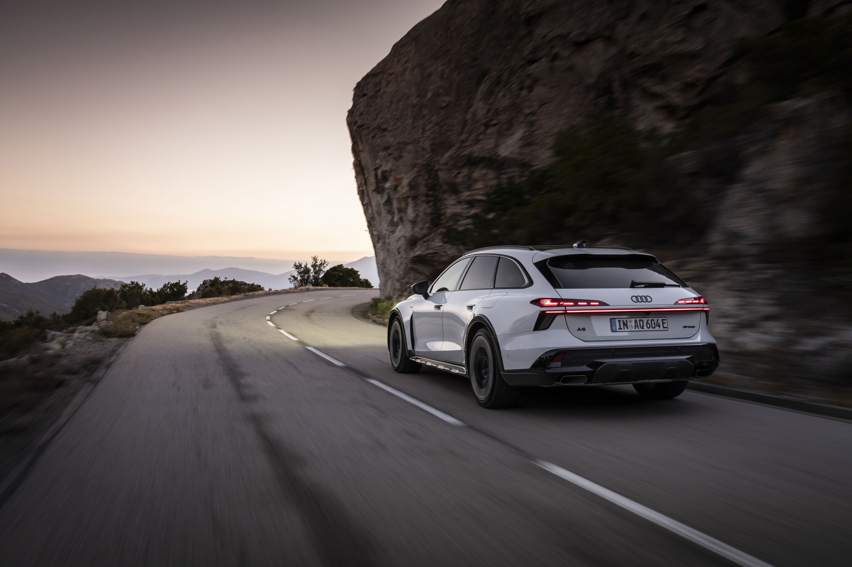 A6 allroad e-hybrid - Audi A6 allroad e-hybrid in Glacier White metallic, outdoor driving shot, exterior, three-quarter rear view in a mountainous setting.