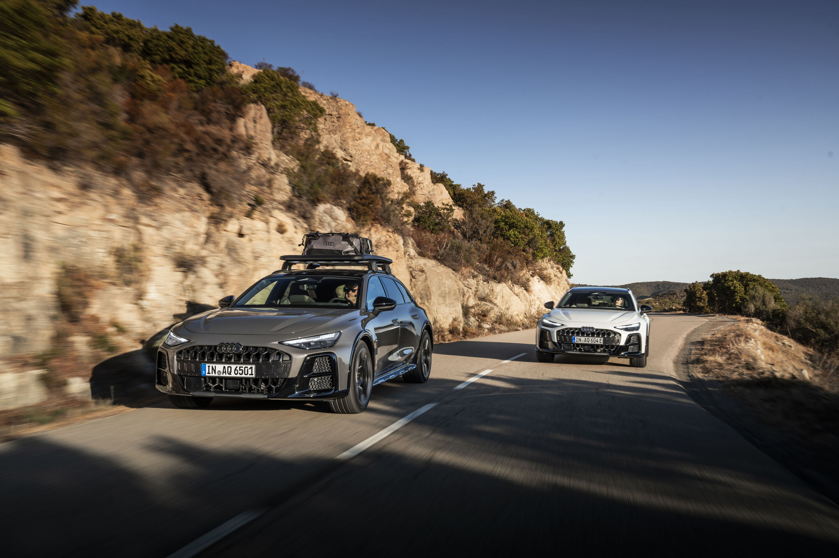 A6 allroad TDI - From left in the picture: Audi A6 allroad TDI in Platinum Gray metallic with roof box, Audi A6 allroad e-hybrid in Glacier White metallic, outdoor driving shot, exterior.